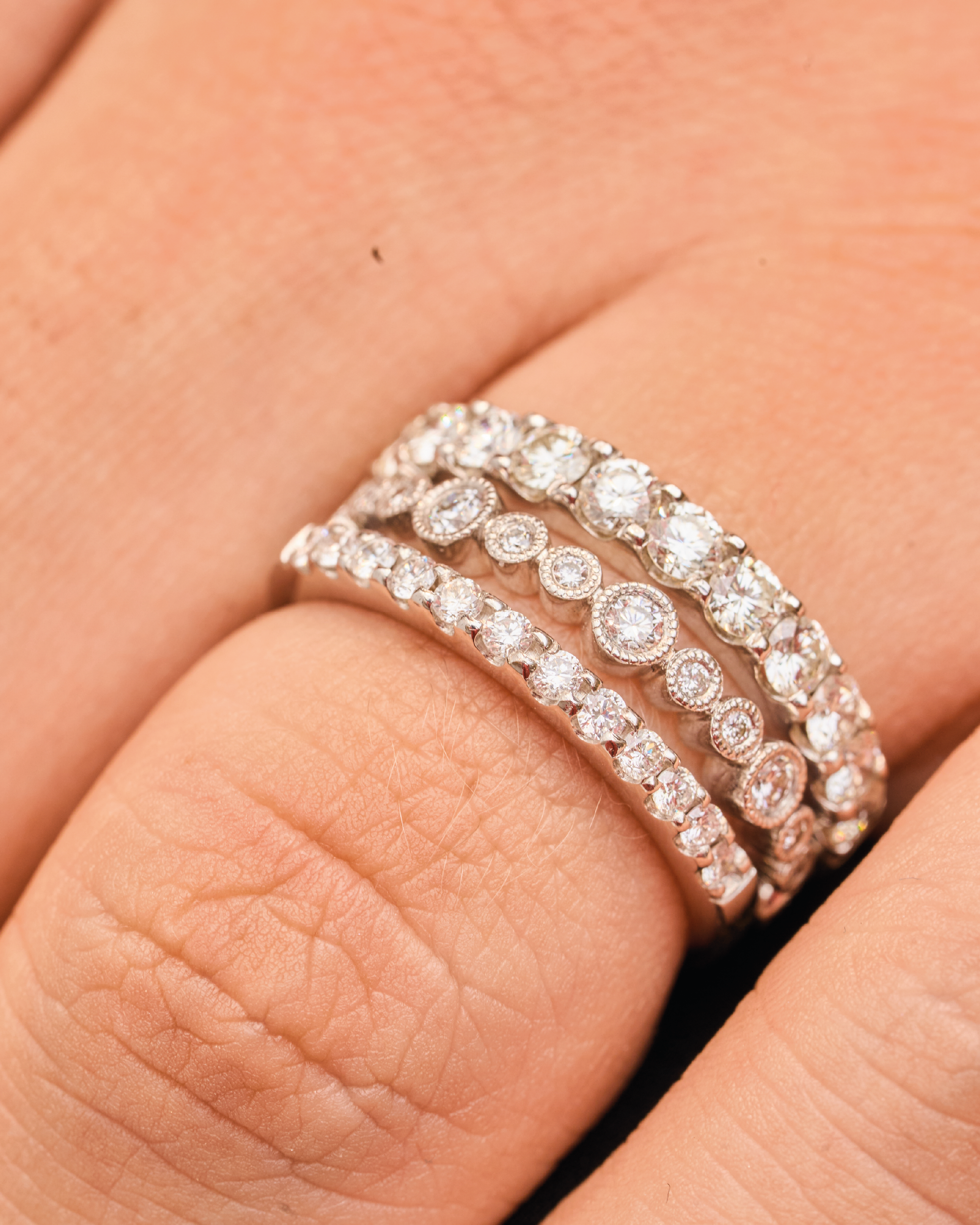 Varios anillos de oro blanco con diamantes en el dedo de una persona