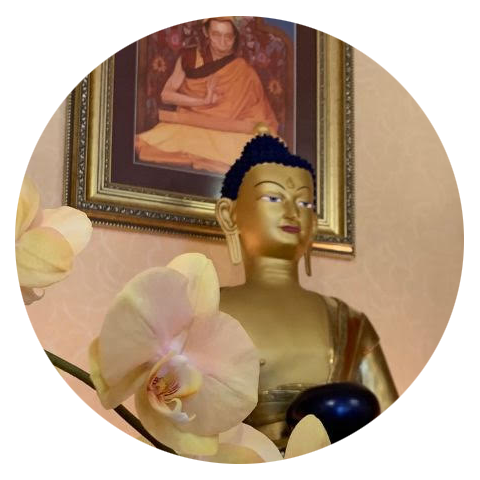 A statue of Buddha Shakyamuni, with a framed portrait of Venerable Geshe Kelsang Gyatso.