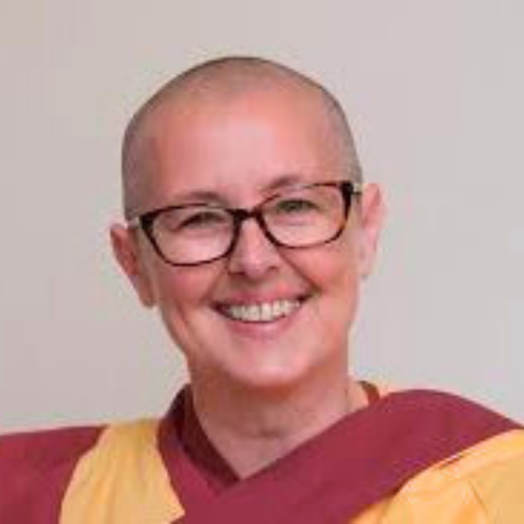 A close-up photo of a smiling woman with short hair and glasses, wearing a maroon and yellow graduation gown.