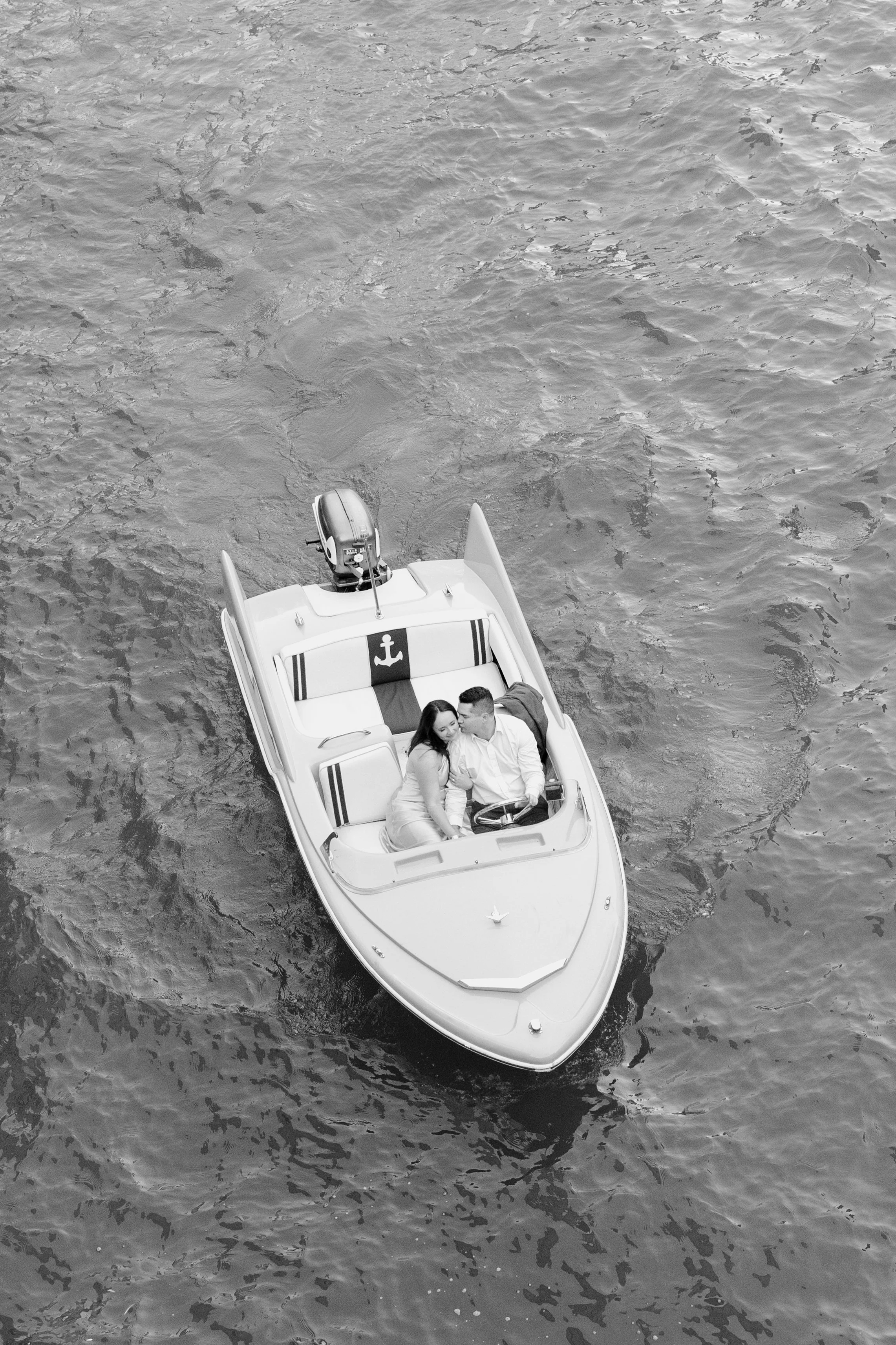 A photo of a boat on a body of water with a couple sitting together on the boat.
