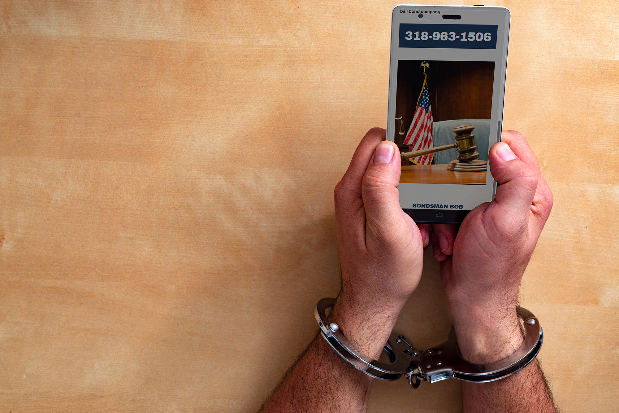 Person in handcuffs holding a smartphone showing a courtroom scene with a gavel, American flag, and a label reading 'BONDMAN BOB'.