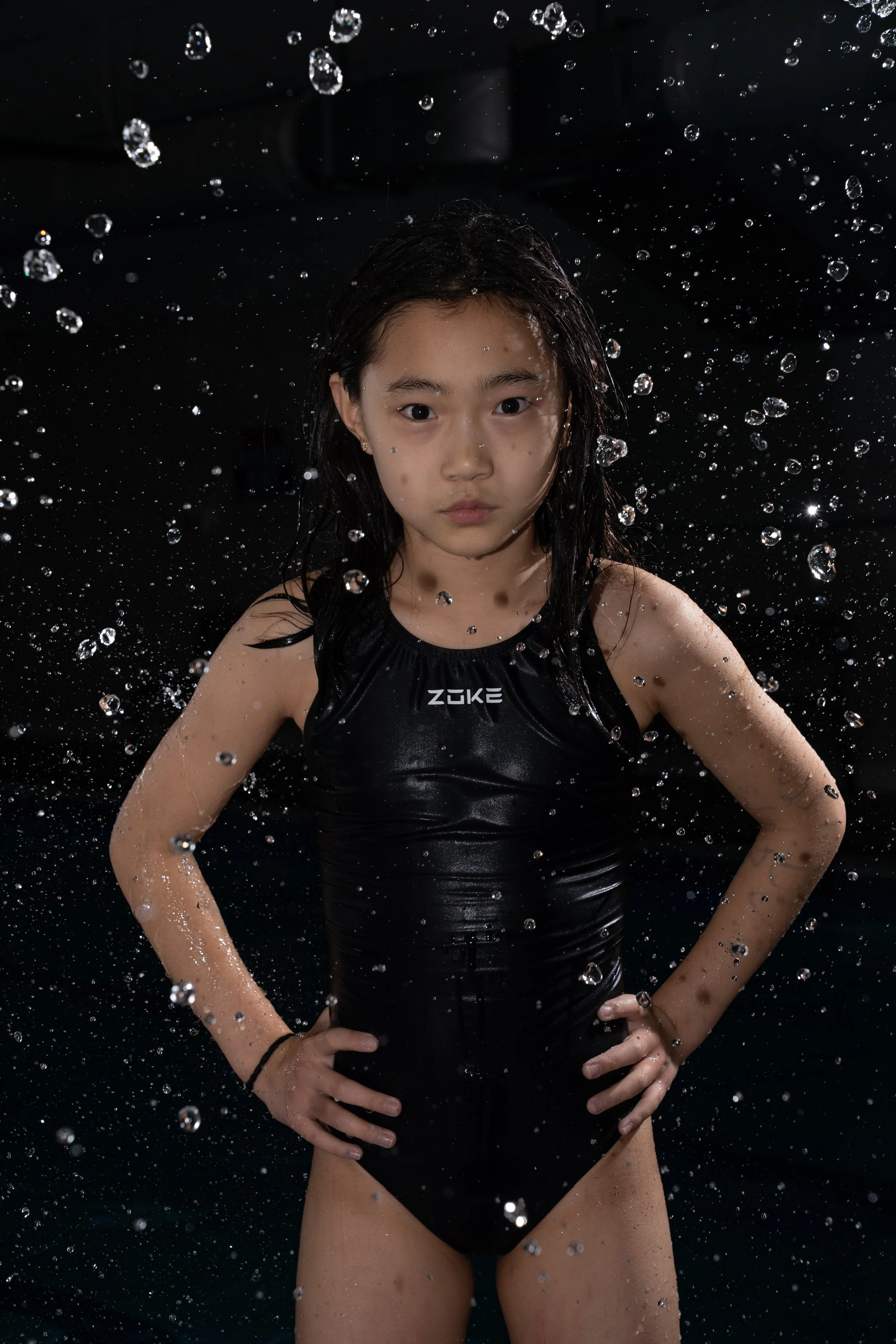 Athletic child portrait with water splash, studio lighting emphasizing strength and motion