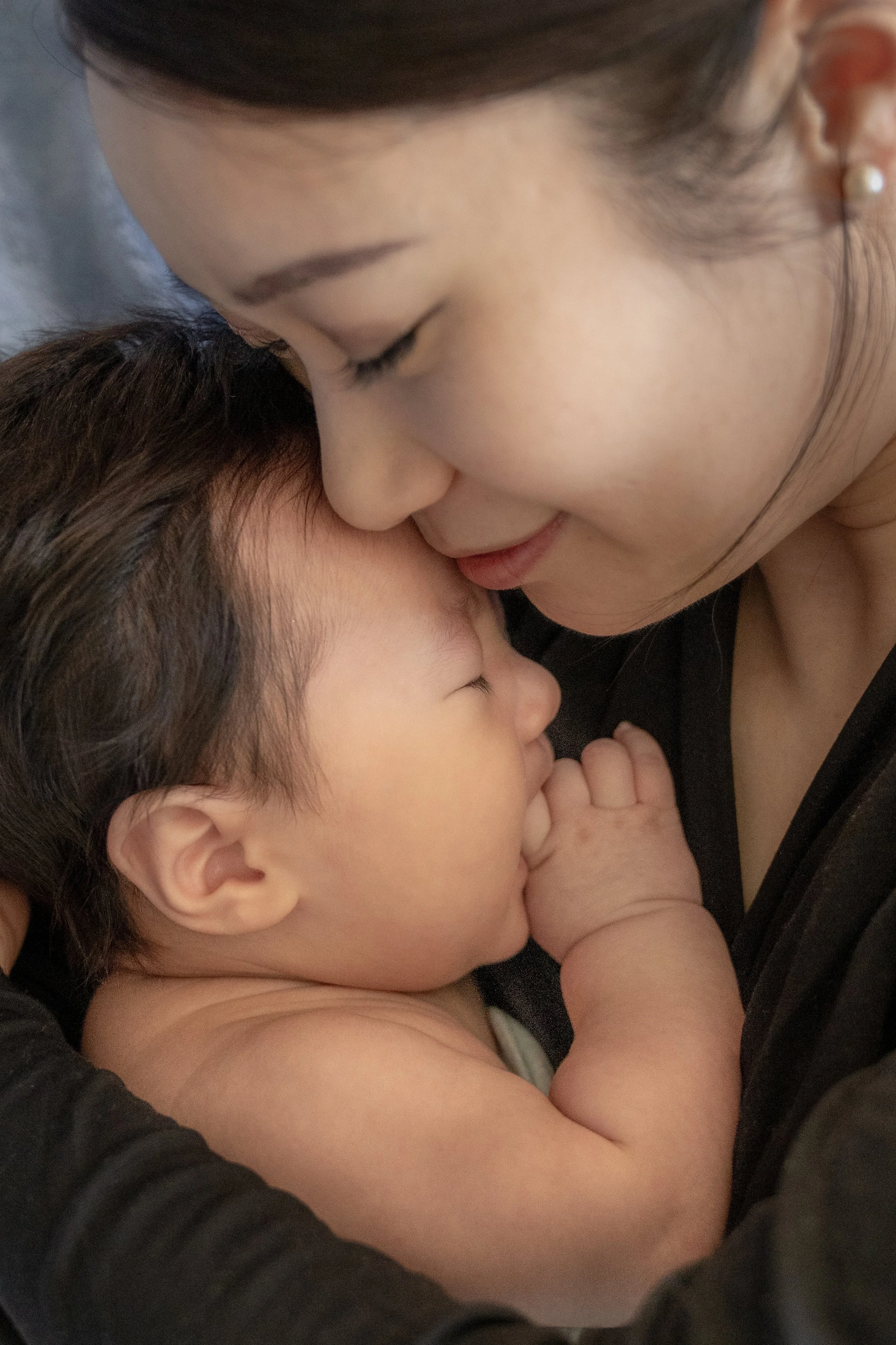 A woman and a young child sharing a tender moment, with the woman gently touching her forehead to the child's.