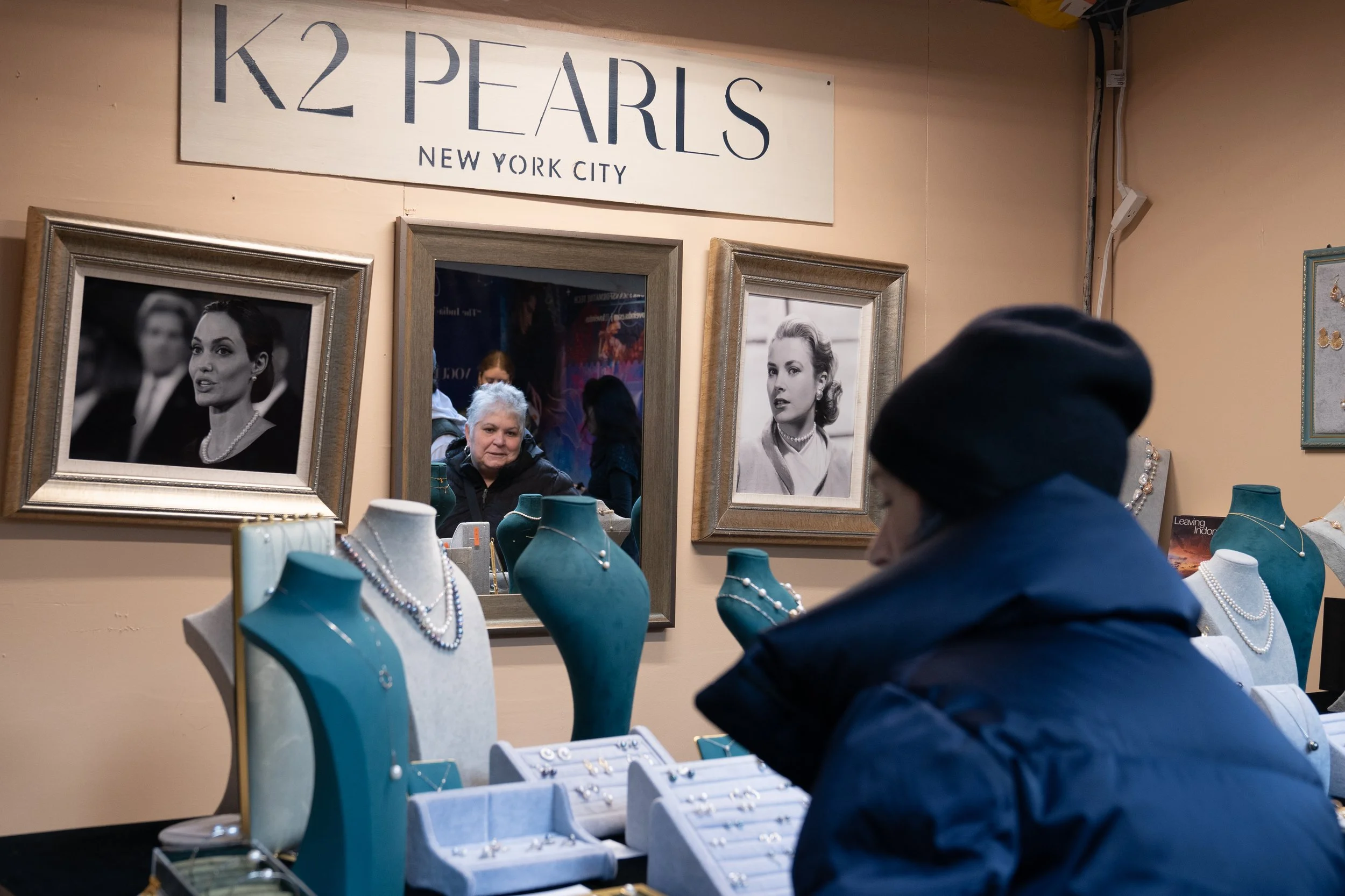 A customer inside a jewelry shop with display busts and framed portraits on the wall