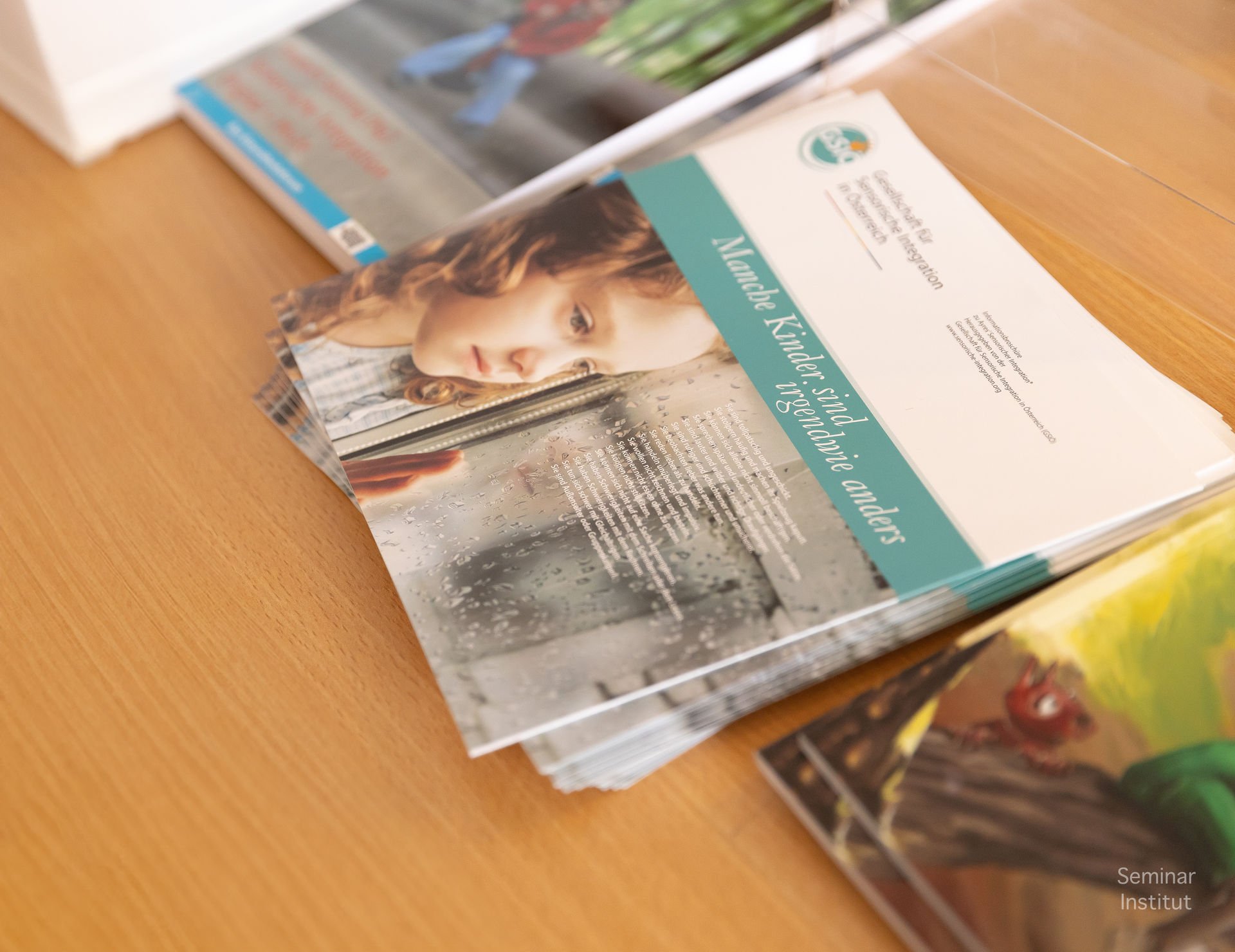 Druckexemplar eines Flyers mit dem Titel 'Manuela Künder: Studienorientierung und Beratung', auf einem Holztisch liegend, neben weiteren Flyern und Broschüren.