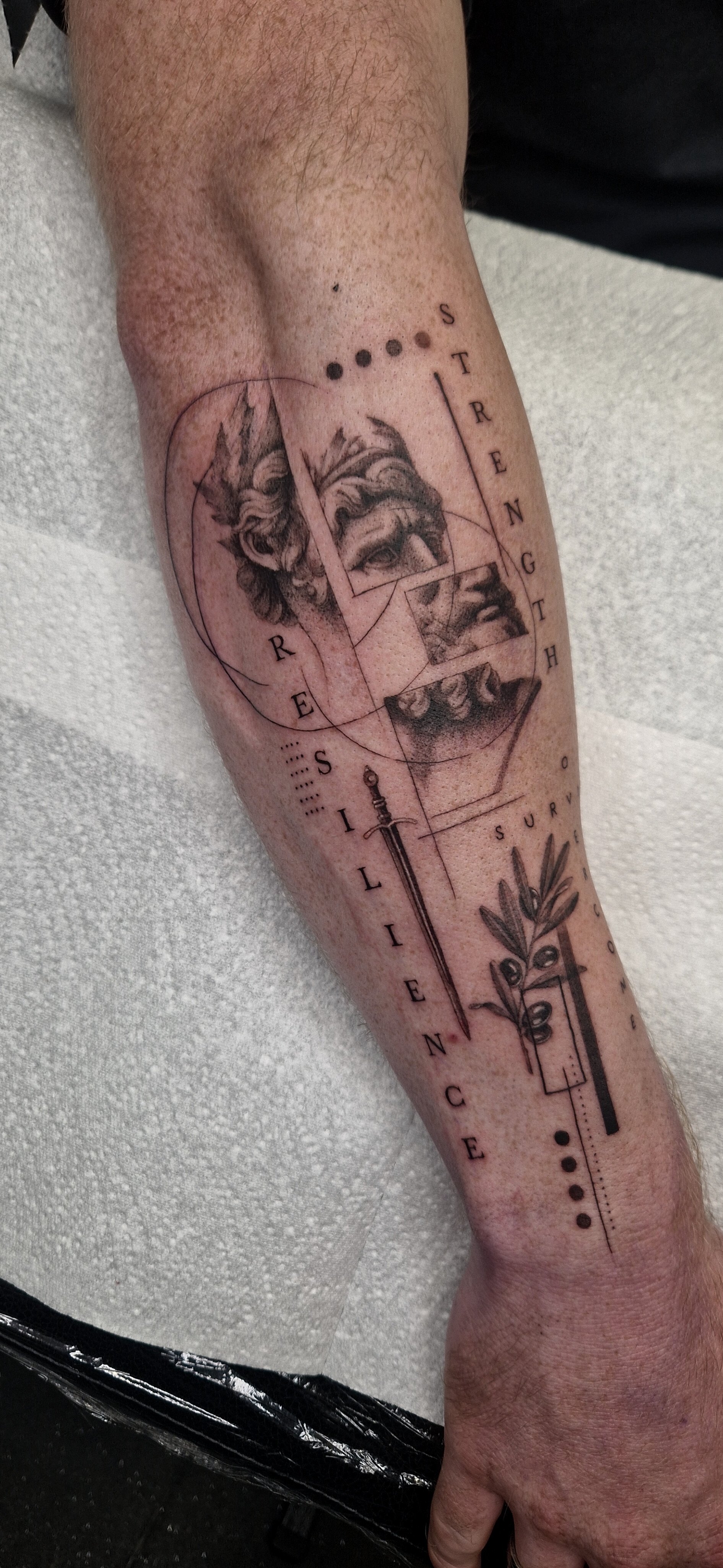 Micro-realism fine line concept tattoo on a person's forearm featuring a classical sculpture of a face, geometric lines, a sword, and the words 'Resilience' and 'Strength'.