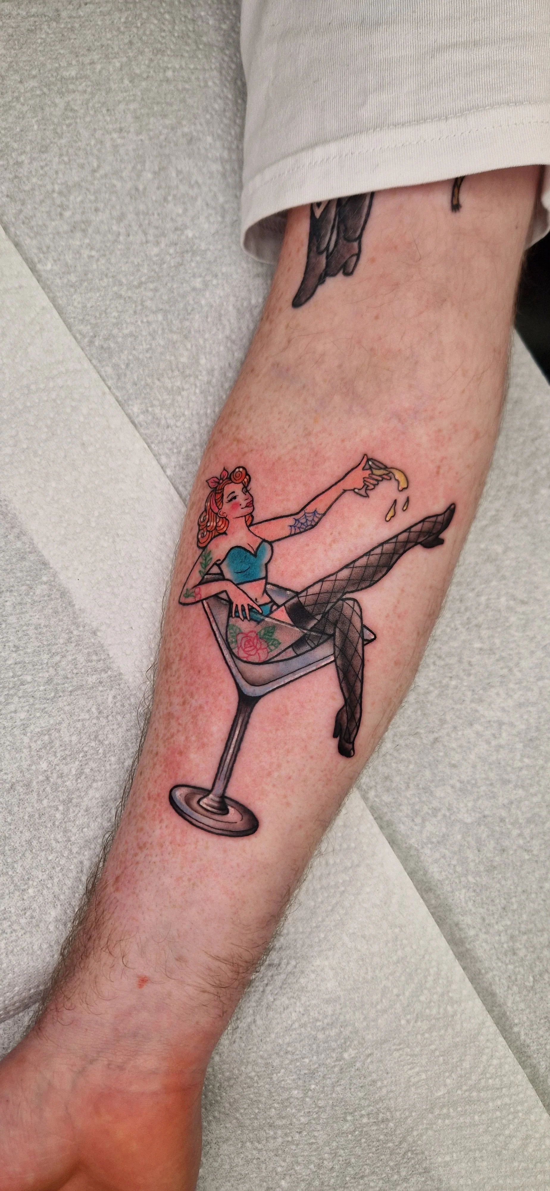 Pin-up girl in a sailor jerry traditional tattoo style, sitting in a martini glass drinking a martini.