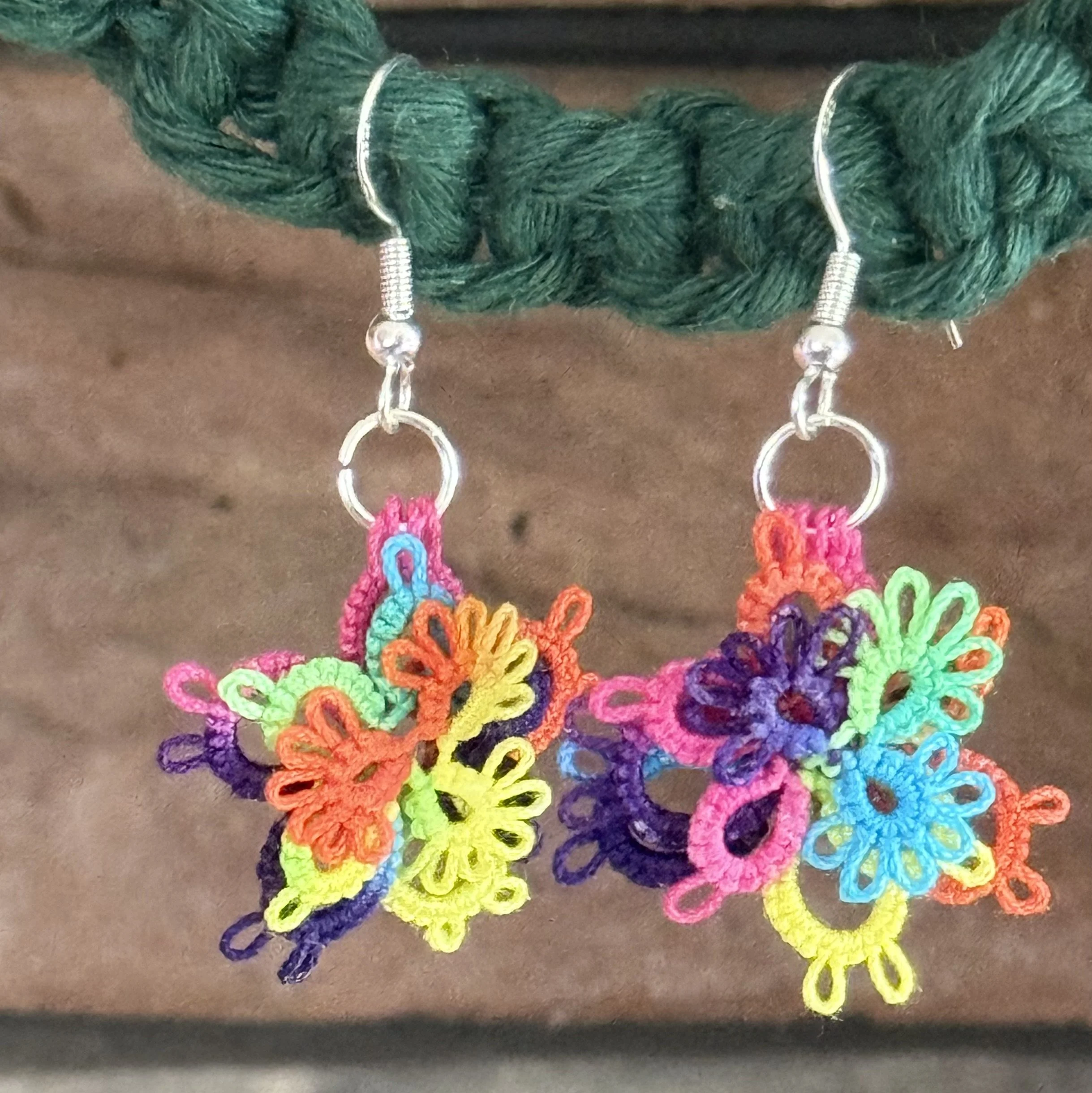 Colorful embroidered butterfly earrings hanging from silver hooks on a green string.