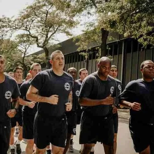 Group of men wearing black athletic shirts and shorts jogging outdoors