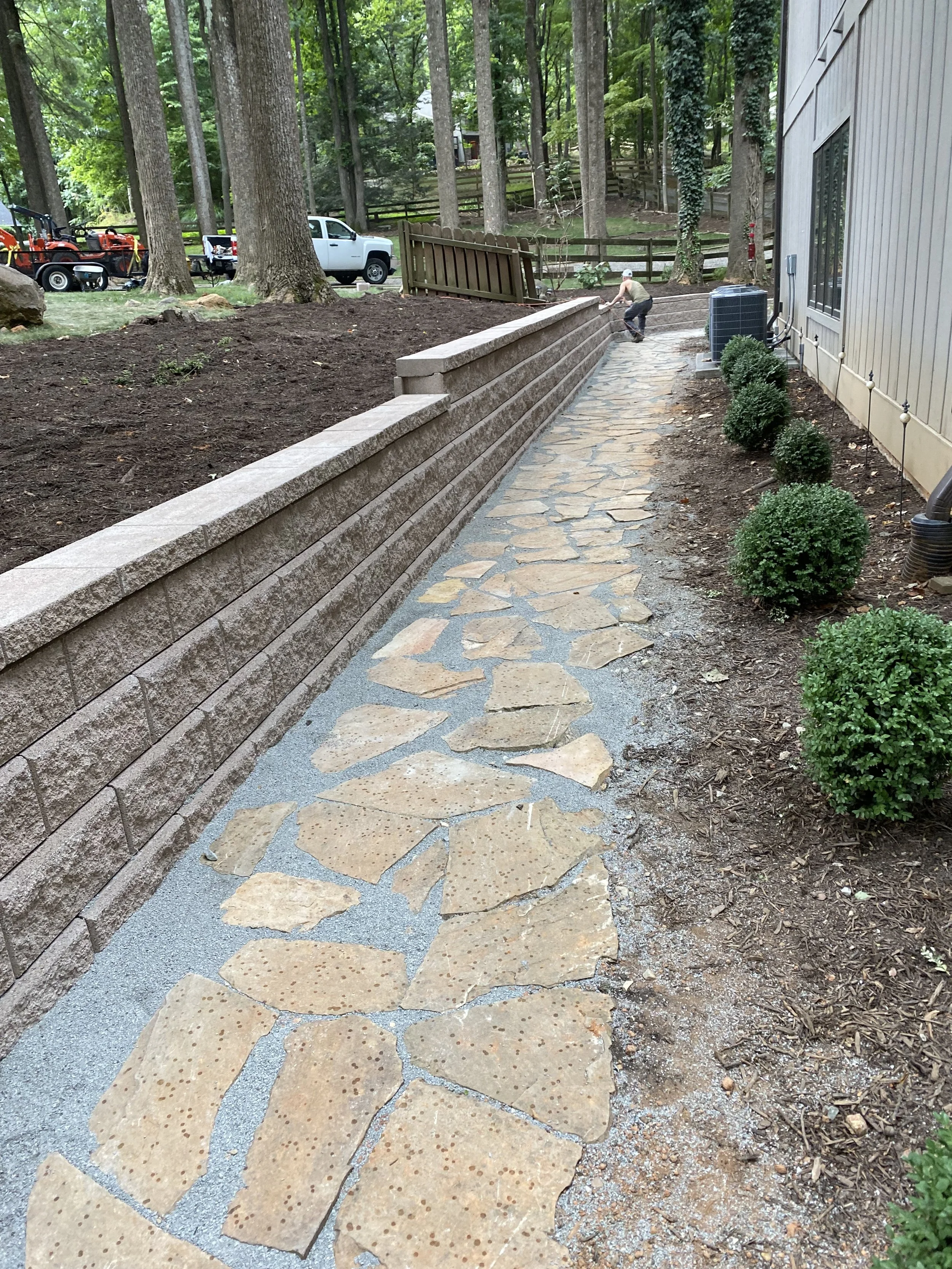 a newly constructed retaining wall with a flag stone walk way beside it
