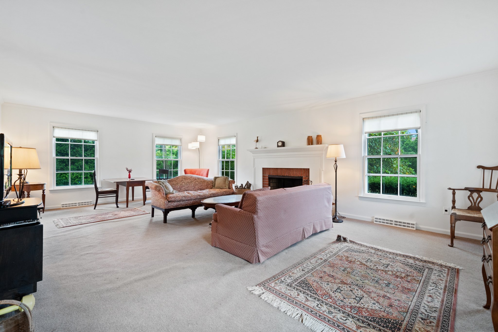 Living room with large windows, pink sofas, a fireplace, and various small decorative items.