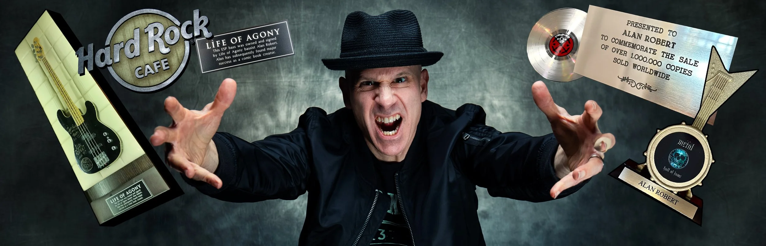 A man wearing a black hat and jacket, making an aggressive expression with his mouth open and hands extended. Surrounding him are various awards and memorabilia including a guitar-shaped plaque, a music award for the album "Life of Agony," a gold record plaque, and a Hard Rock Cafe sign.