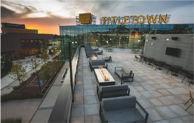 Rooftop patio with seating and fire pits at sunset, with the word 'TILETOWN' in large letters on a building in the background.