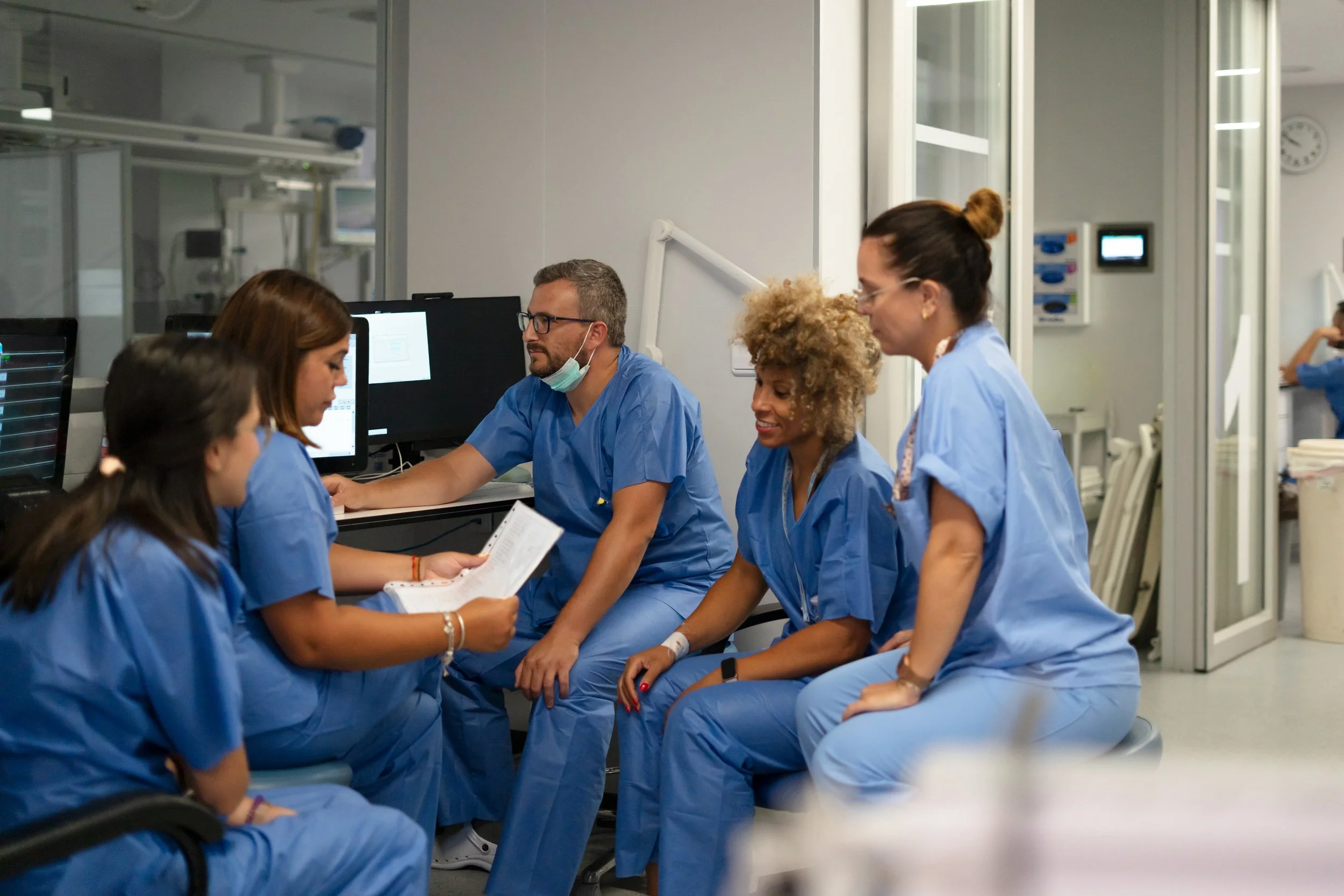 Medical team in scrubs having a discussion in a hospital room.