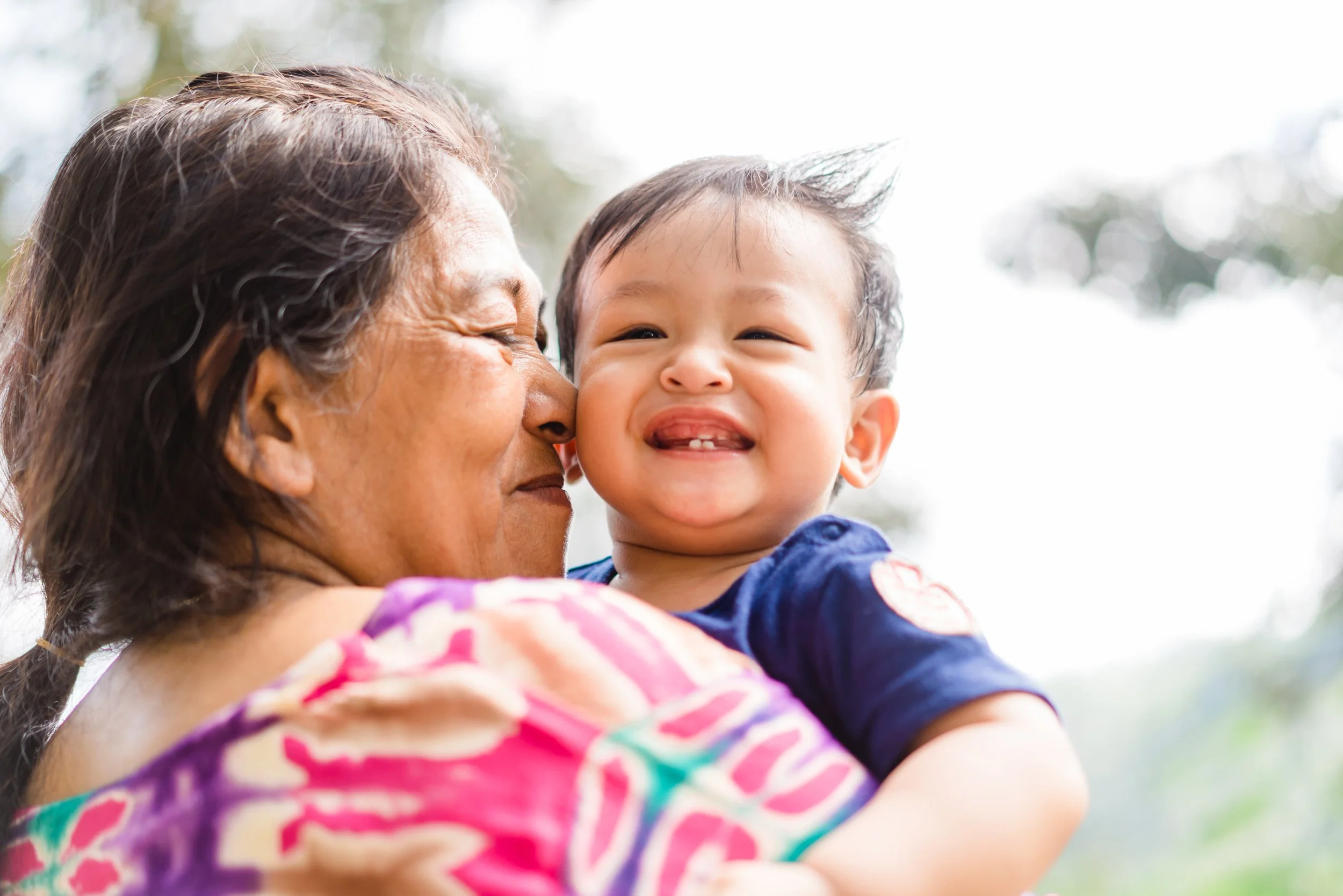 Grandmother holding a smiling baby outdoors.