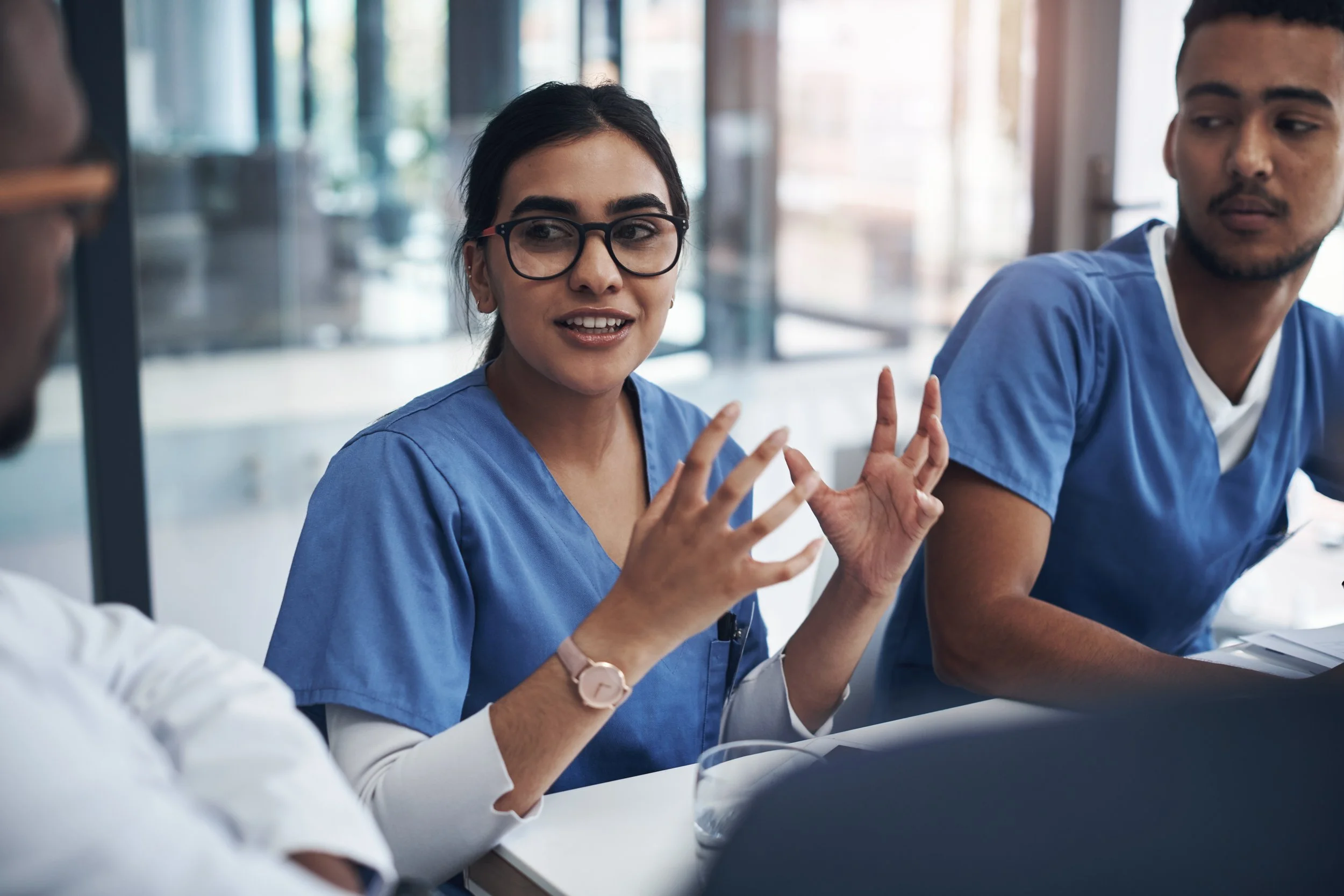 Medical professionals in scrubs having a discussion in a meeting room.