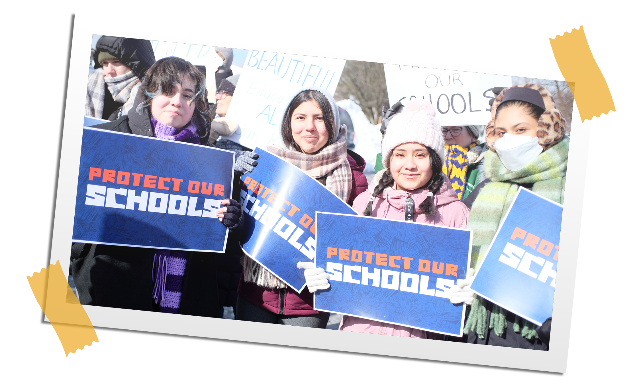 Group of children holding signs that read 'Protect Our Schools' during a rally outdoors in winter.