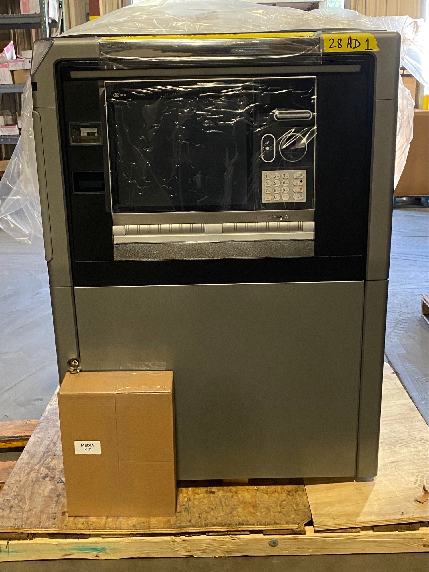 A bank of ATMs or vending machines with a cardboard box labeled "Media Kit" placed in front of it.