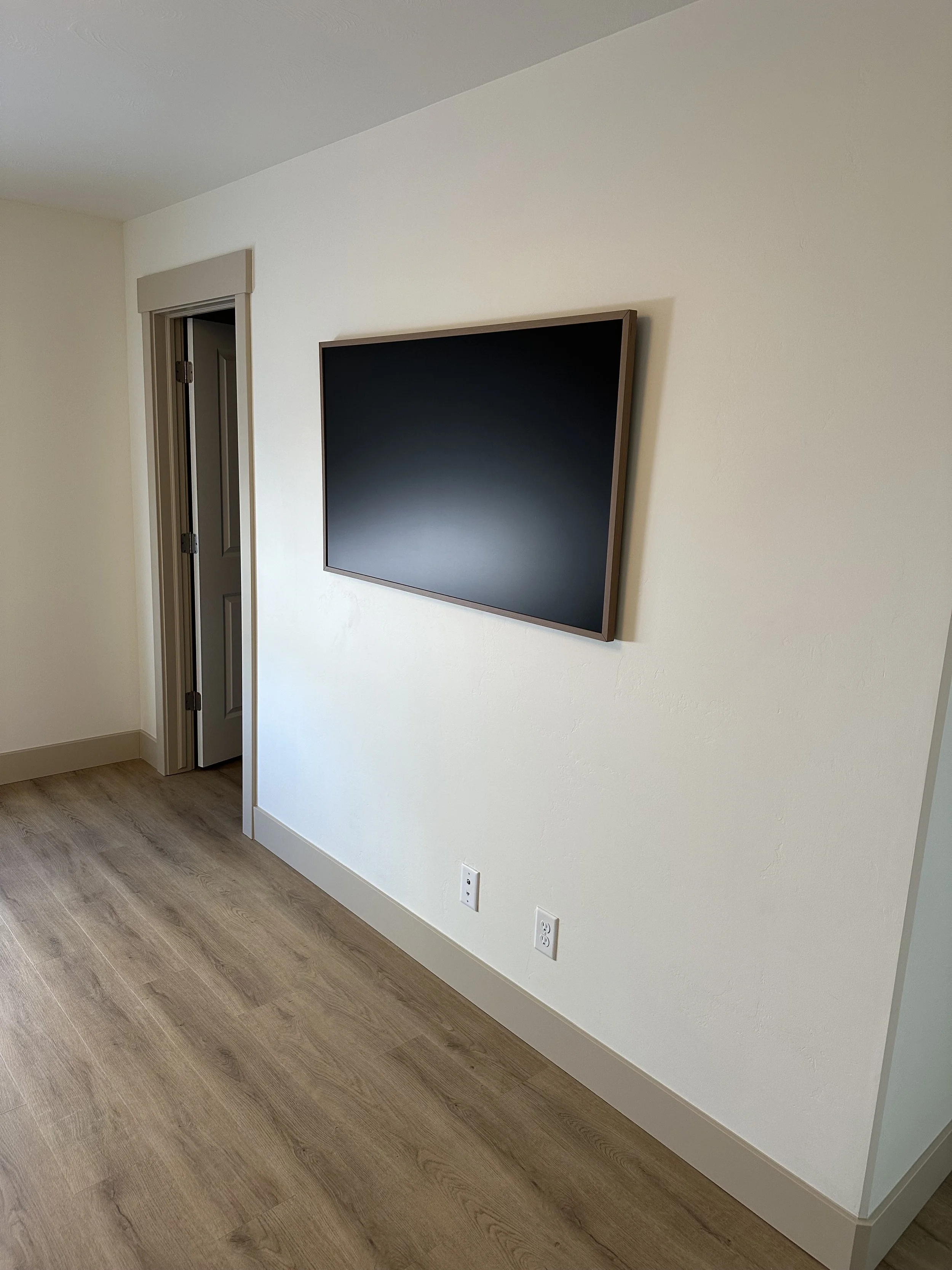 Empty room with a wall-mounted flat-screen TV, a door to a closet, and electrical outlets on the wall.