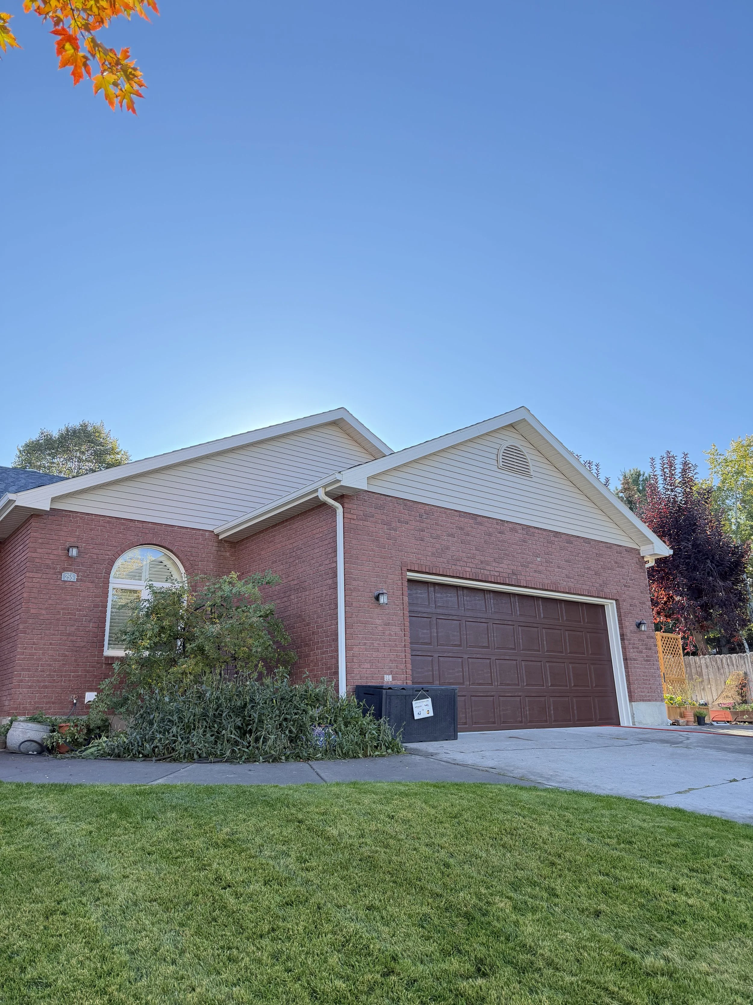 A two-story brick house with a brown garage door, white trim, and a well-kept green lawn.