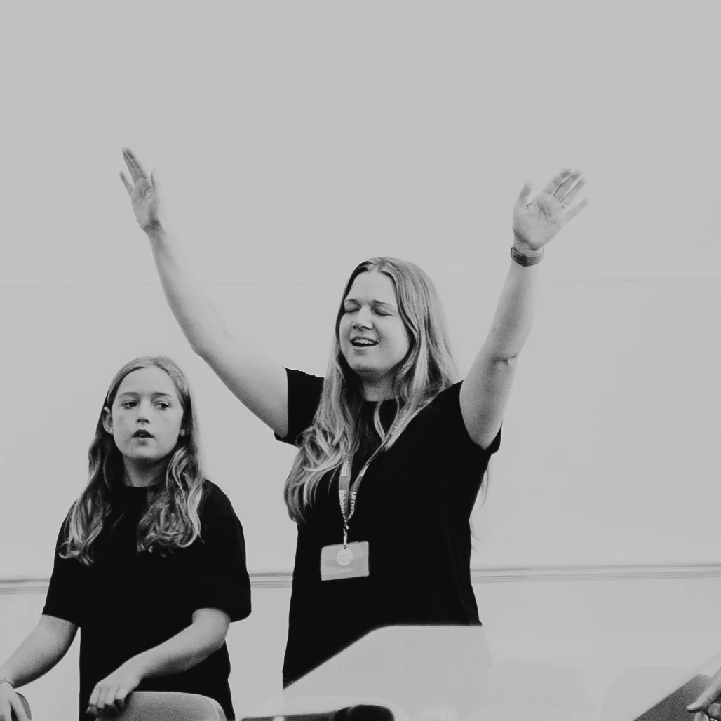 Black and white image of woman with hands raised in worship