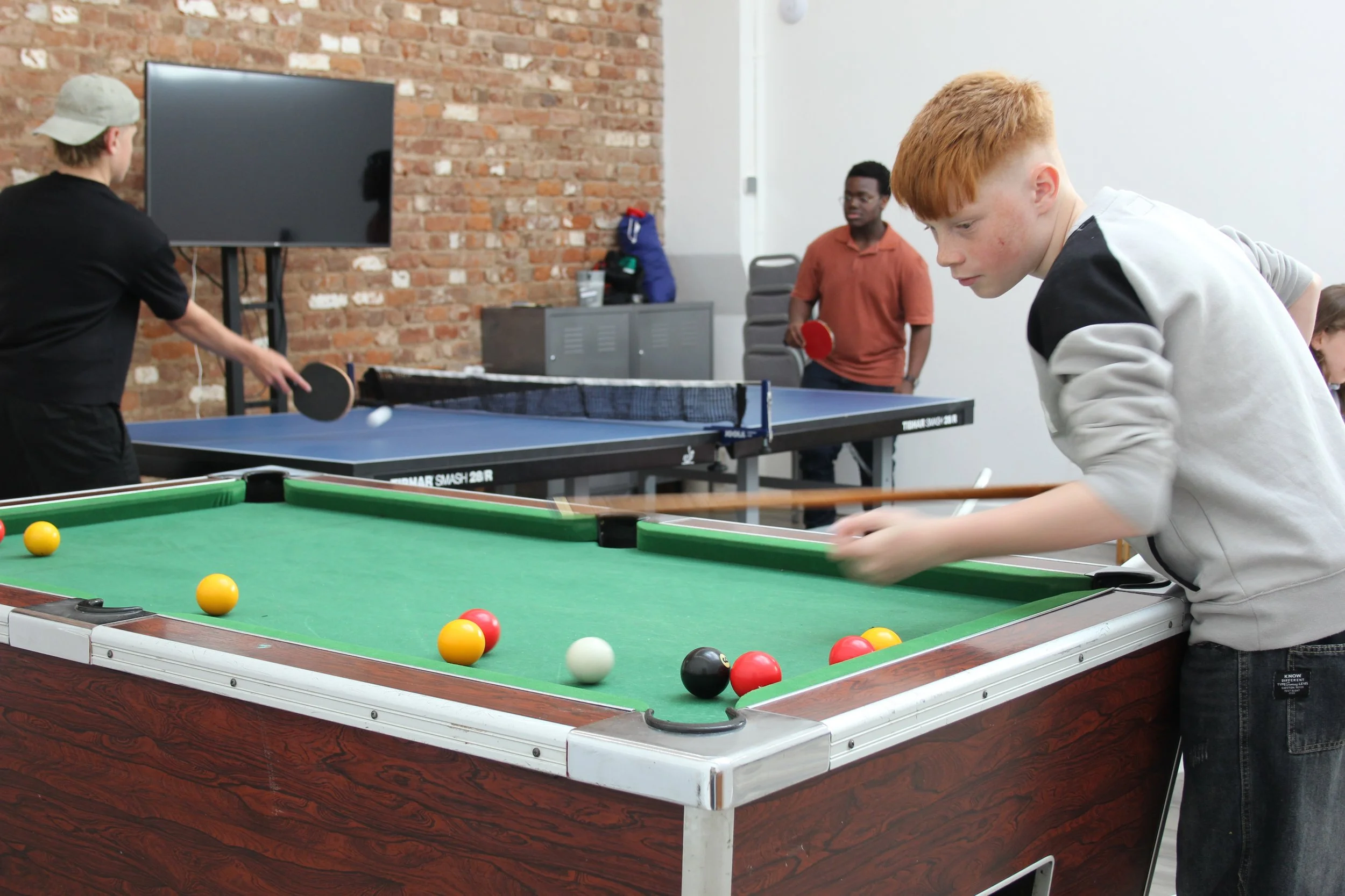 Boys in youth playing table tennis and pool