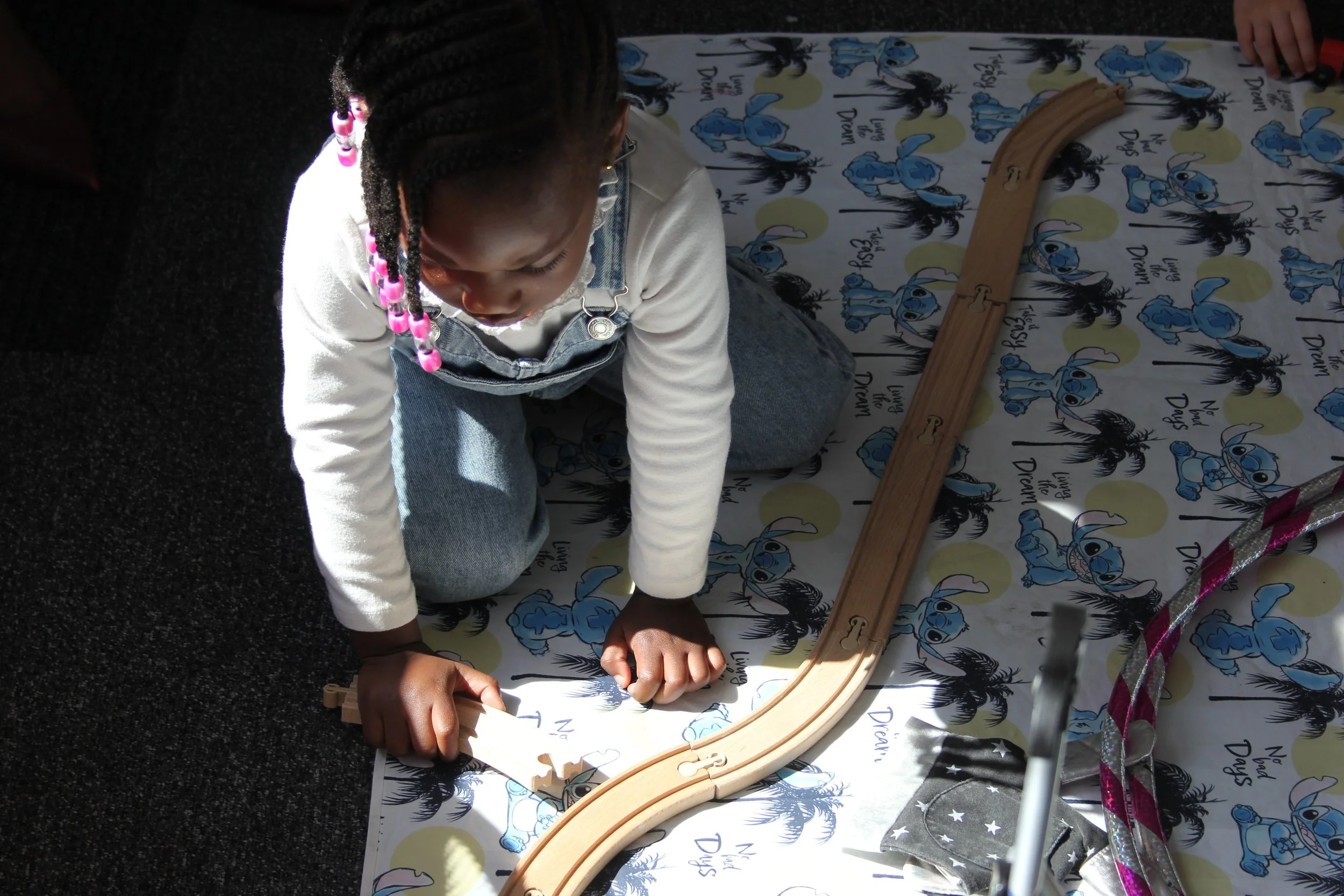 Young girl playing with a train track during Lifehouse kids