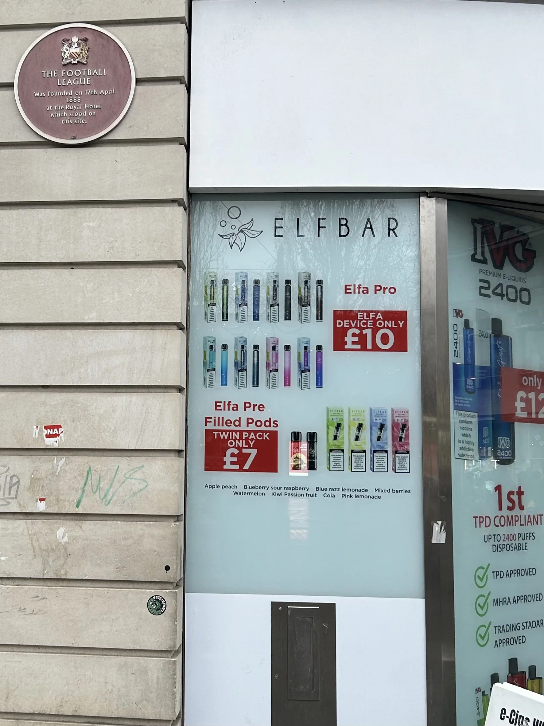 Store window advertising Elfbar vaping products, including Elfbar Pro for £10 and pre-filled Elfbar pods for £7, with flavor options listed below.