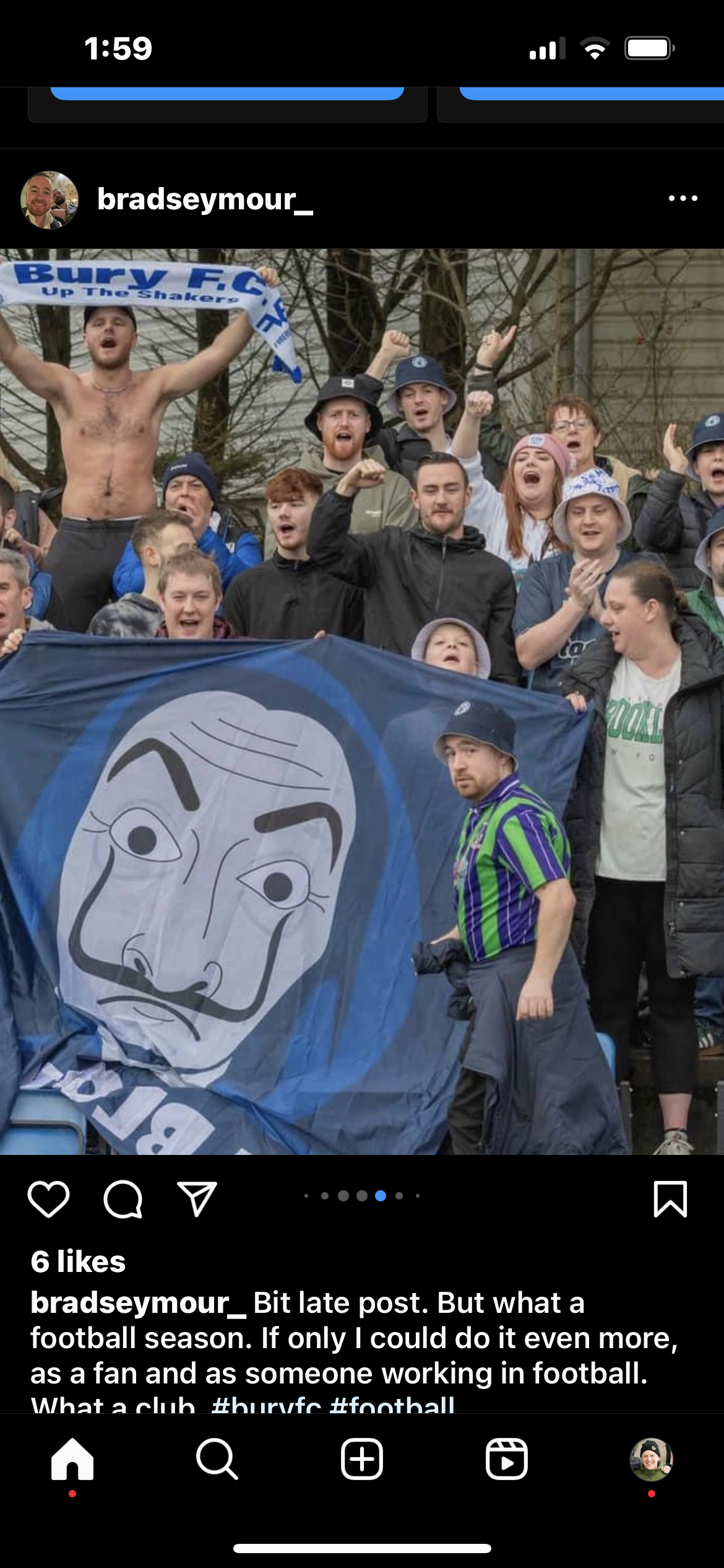 A group of football fans, some wearing Hurl FC scarves and hats, cheering and celebrating outdoors. A person in a green and purple striped shirt and bucket hat stands in front of a Hurl FC flag featuring a stylized face.