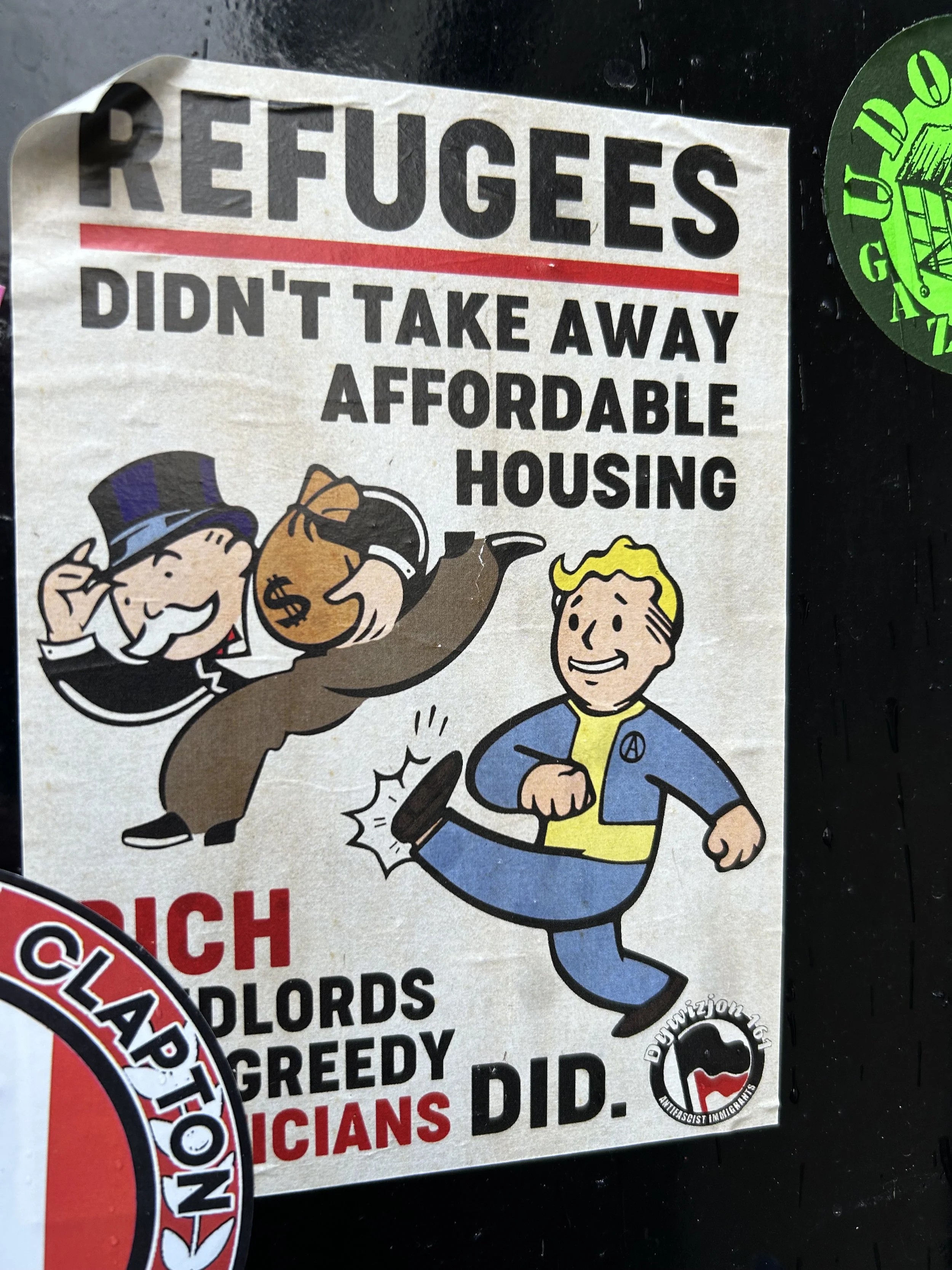 Poster criticizing wealthy landlords for taking away affordable housing from refugees, featuring Monopoly-style characters and bold text.
