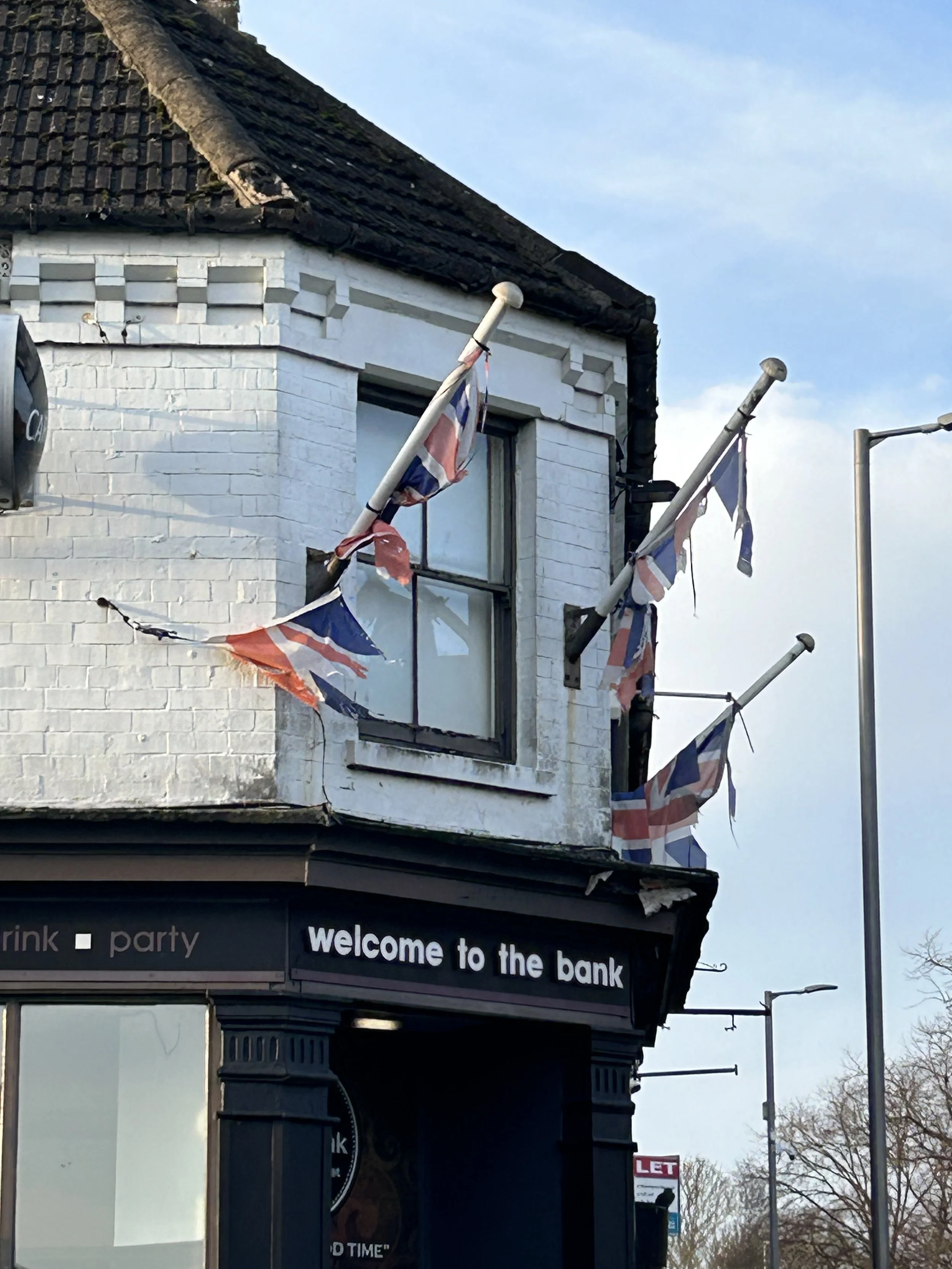 Building with Union Jack flags hanging from poles and a sign that says 'welcome to the bank'.