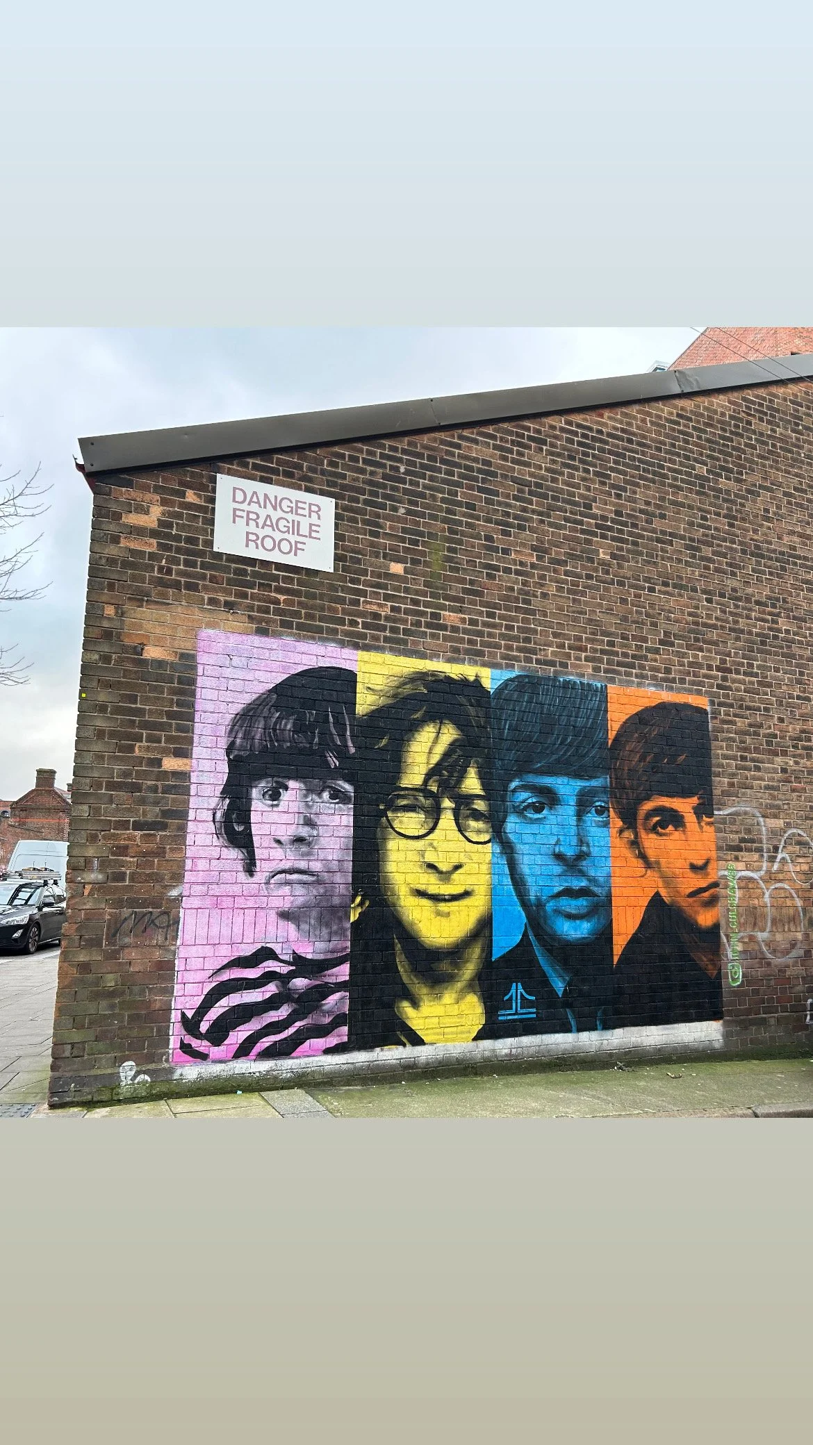 Colorful graffiti mural of four faces on a brick wall.