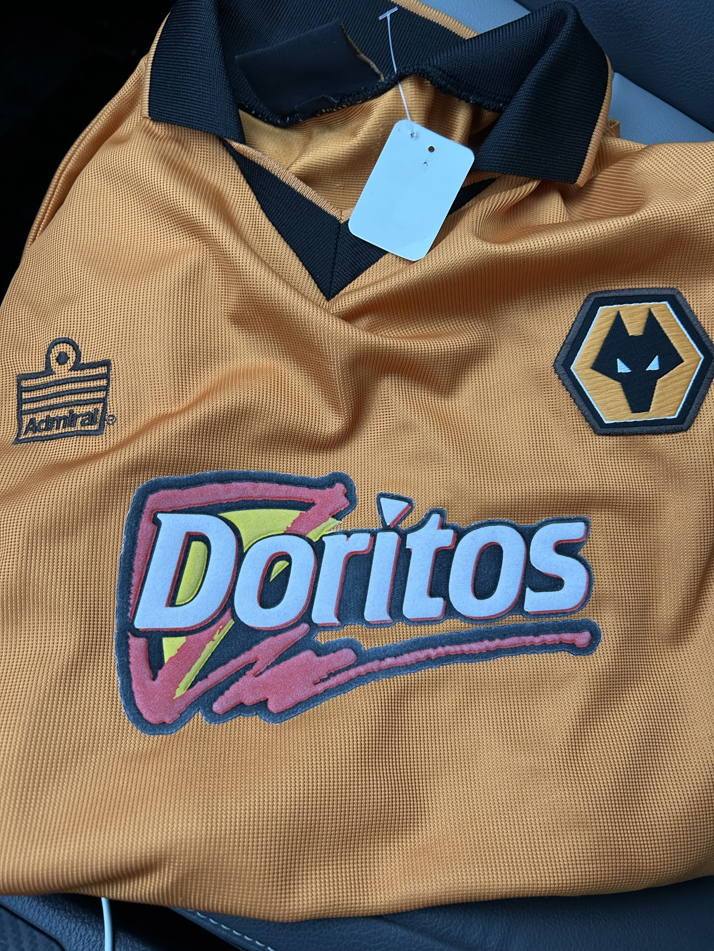 A yellow sports jersey with logos of Adidas, Wolverhampton Wanderers, and Doritos.
