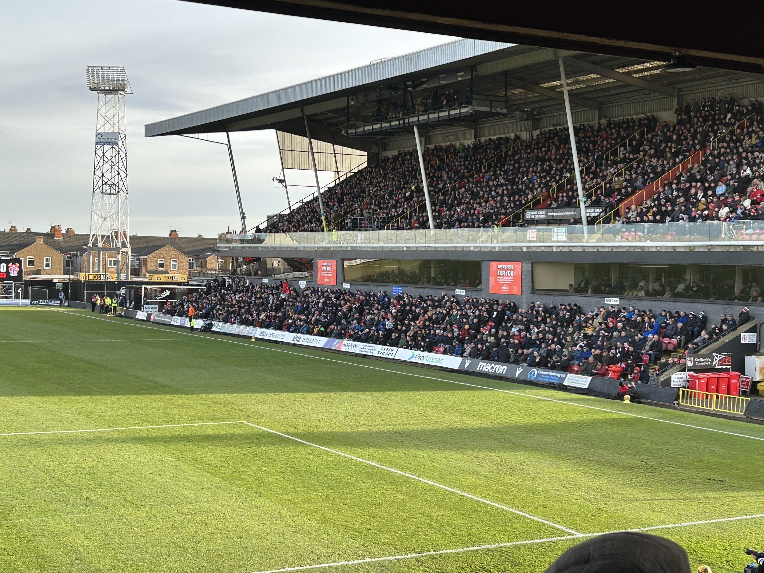 A packed soccer stadium with a crowd of spectators seated in the stands, overlooking a green field.