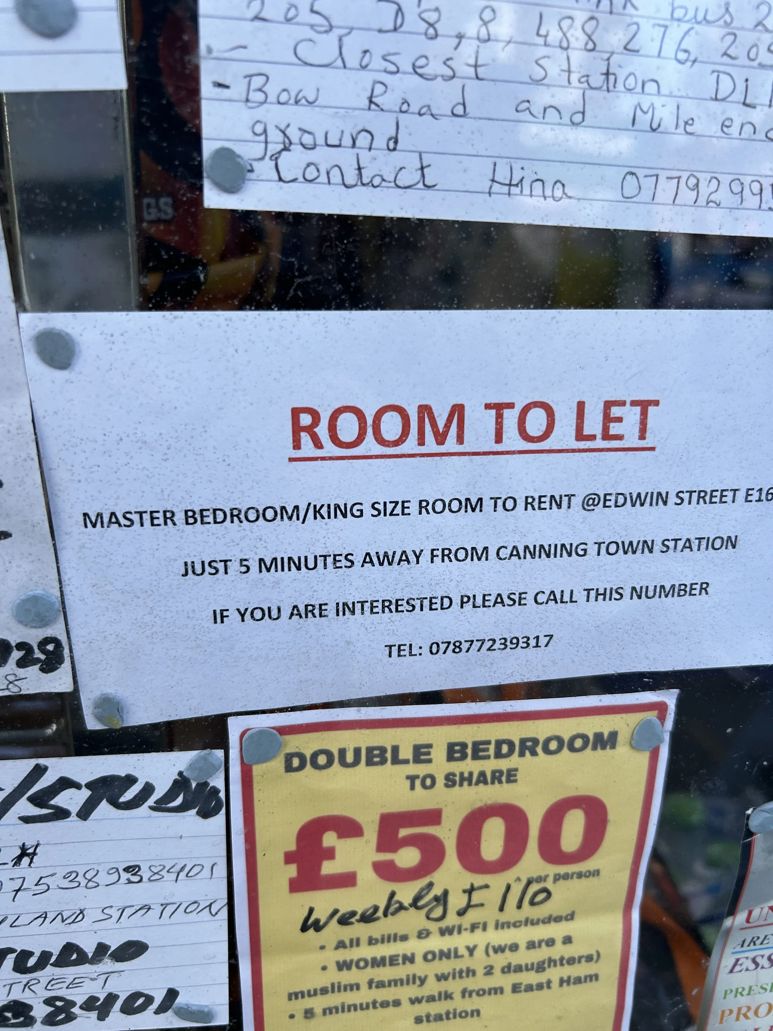 Sign advertising a room to let, a double bedroom for sharing at 500 pounds weekly with Wi-Fi, only for women, near East Ham station. Additionally, a handwritten note with contact information.