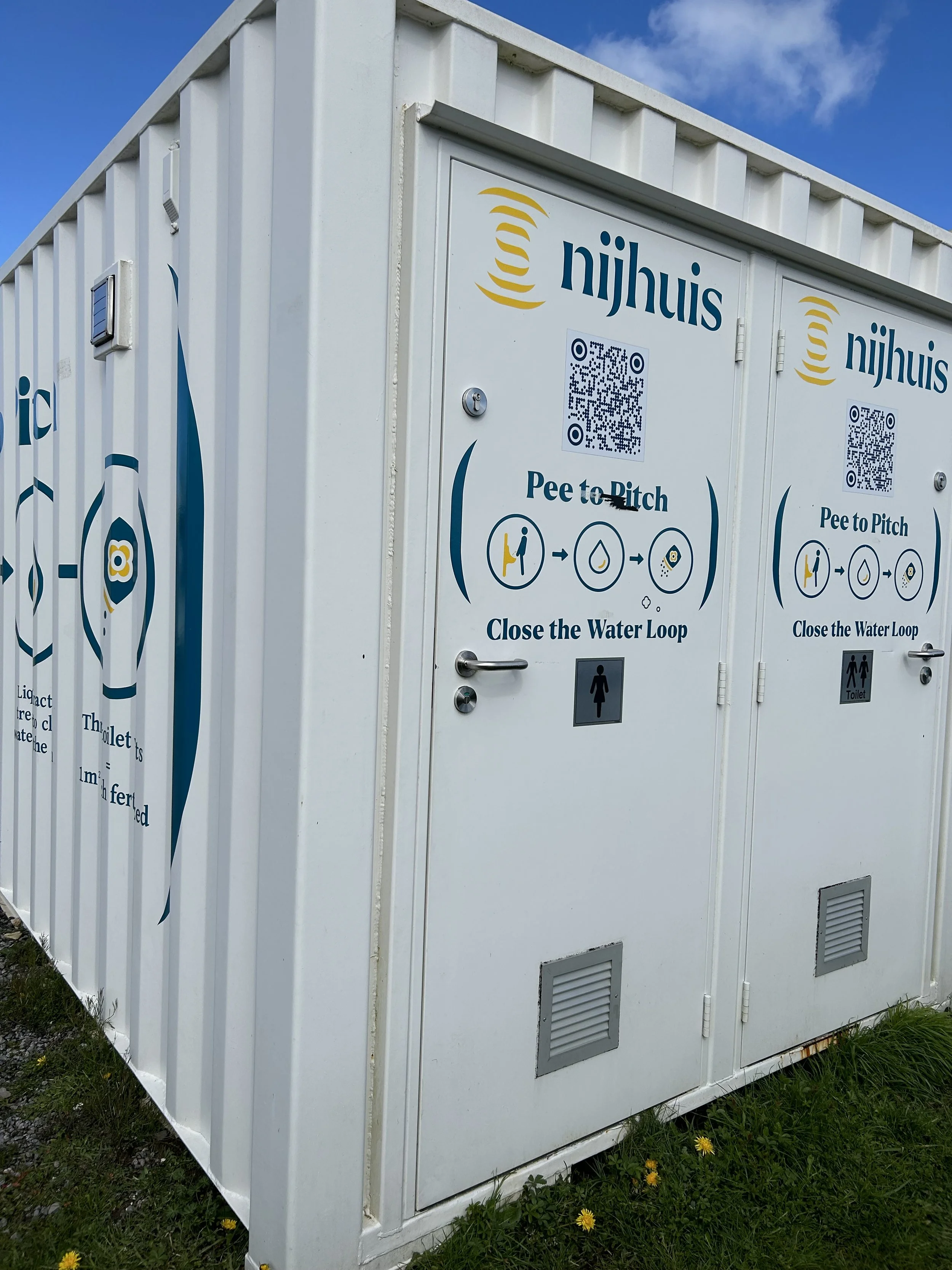 Public toilet facility with outdoor signs explaining how to use the pee to pitch system by closing the water loop, with a QR code and icons for peeing and closing the water loop.