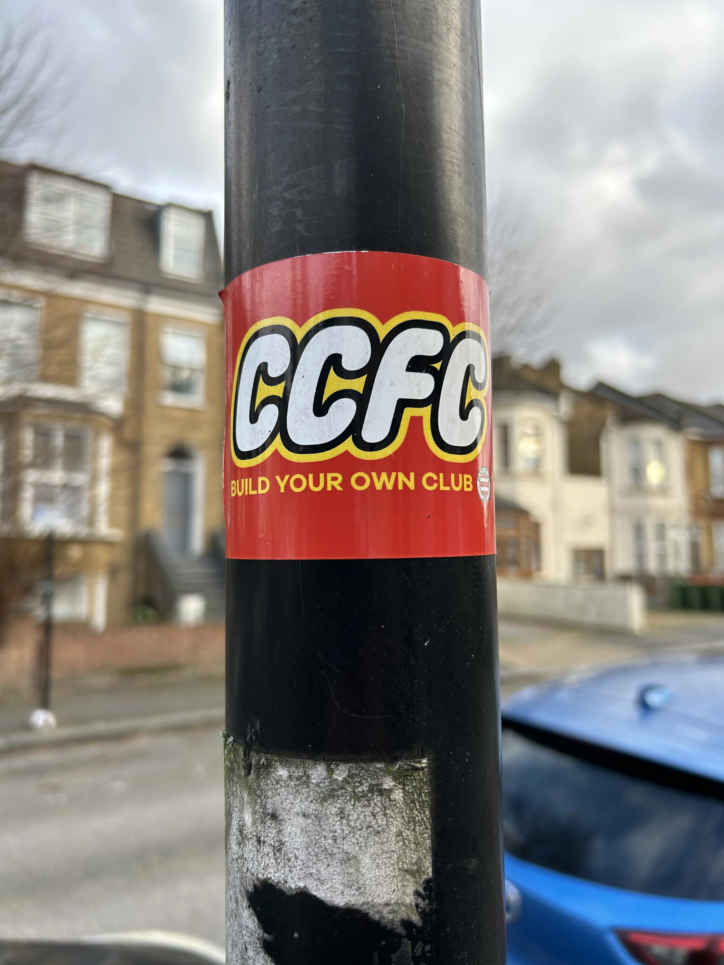 Red sticker on a black pole with the letters 'CCFC' and the phrase 'Build Your Own Club' underneath.