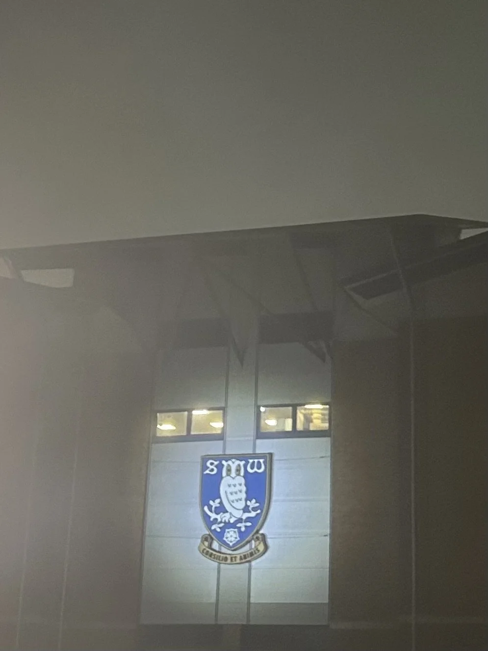 A building with a sign featuring an owl crest and the letters, 'SW,' on it.