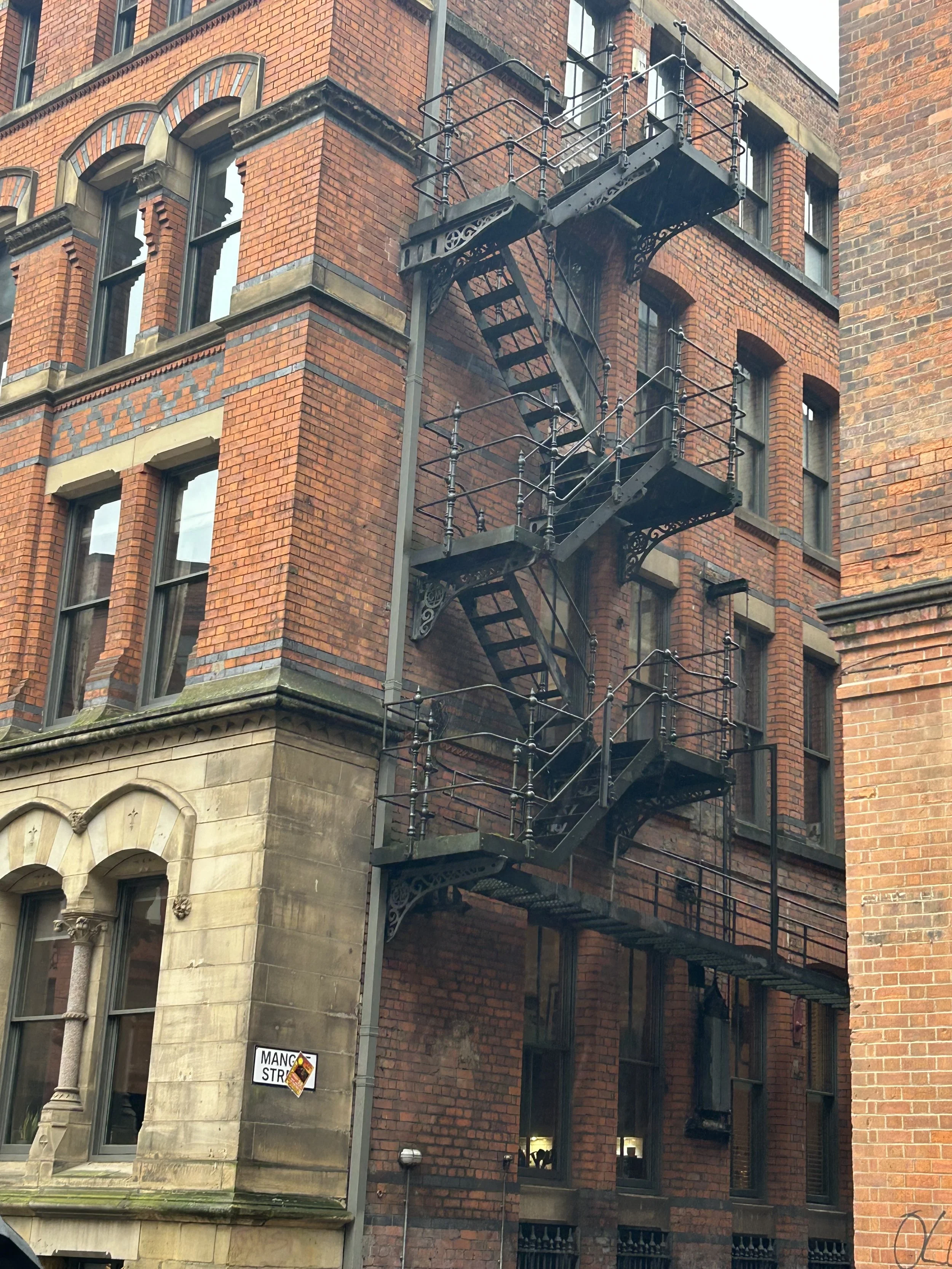 An old brick building with a fire escape staircase on its side.