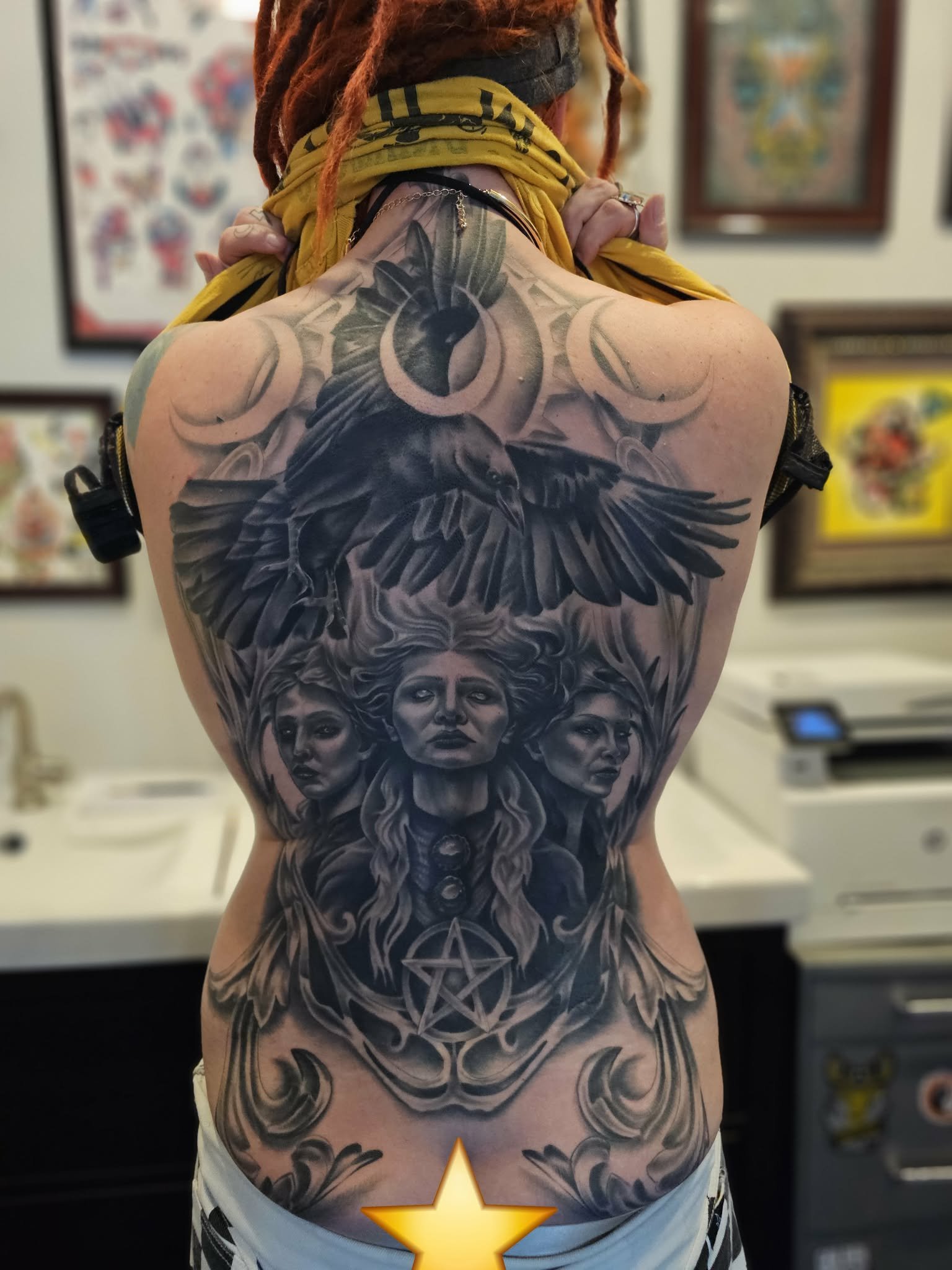 Back tattoo featuring three female faces, an eagle with outstretched wings, a pentagram, and various decorative elements.