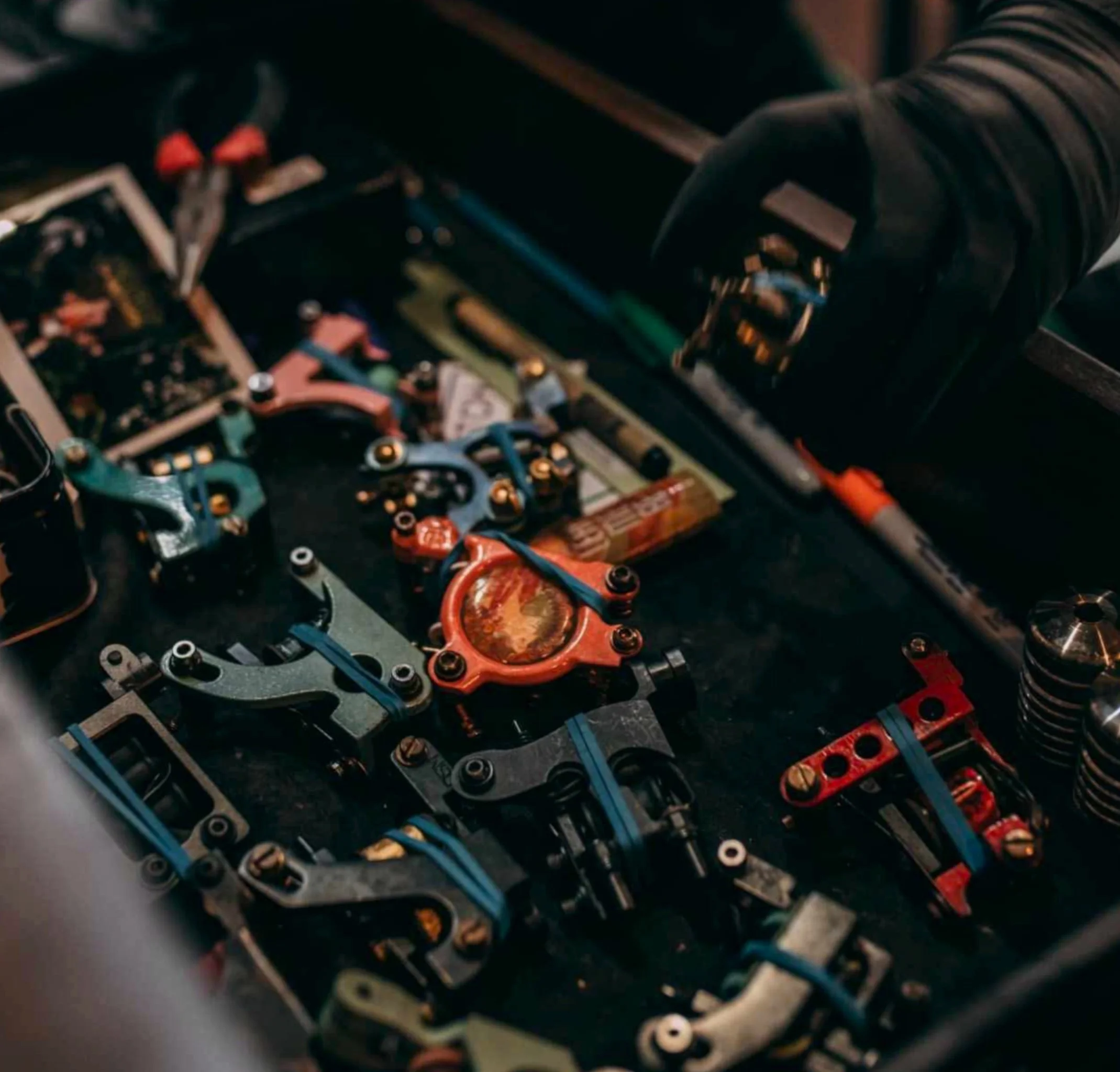 Close-up of a technician's hand working on a miniature remote-controlled car chassis with colorful metal parts and screws.