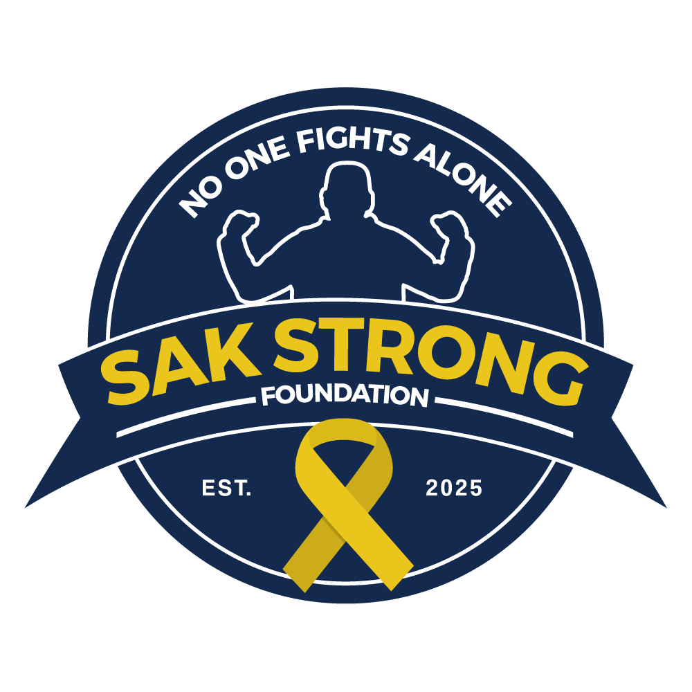 Logo for the Sak Strong Foundation, established in 2025, featuring a muscular silhouette and a yellow awareness ribbon, with the phrases 'No one fights alone' and 'Foundation'.