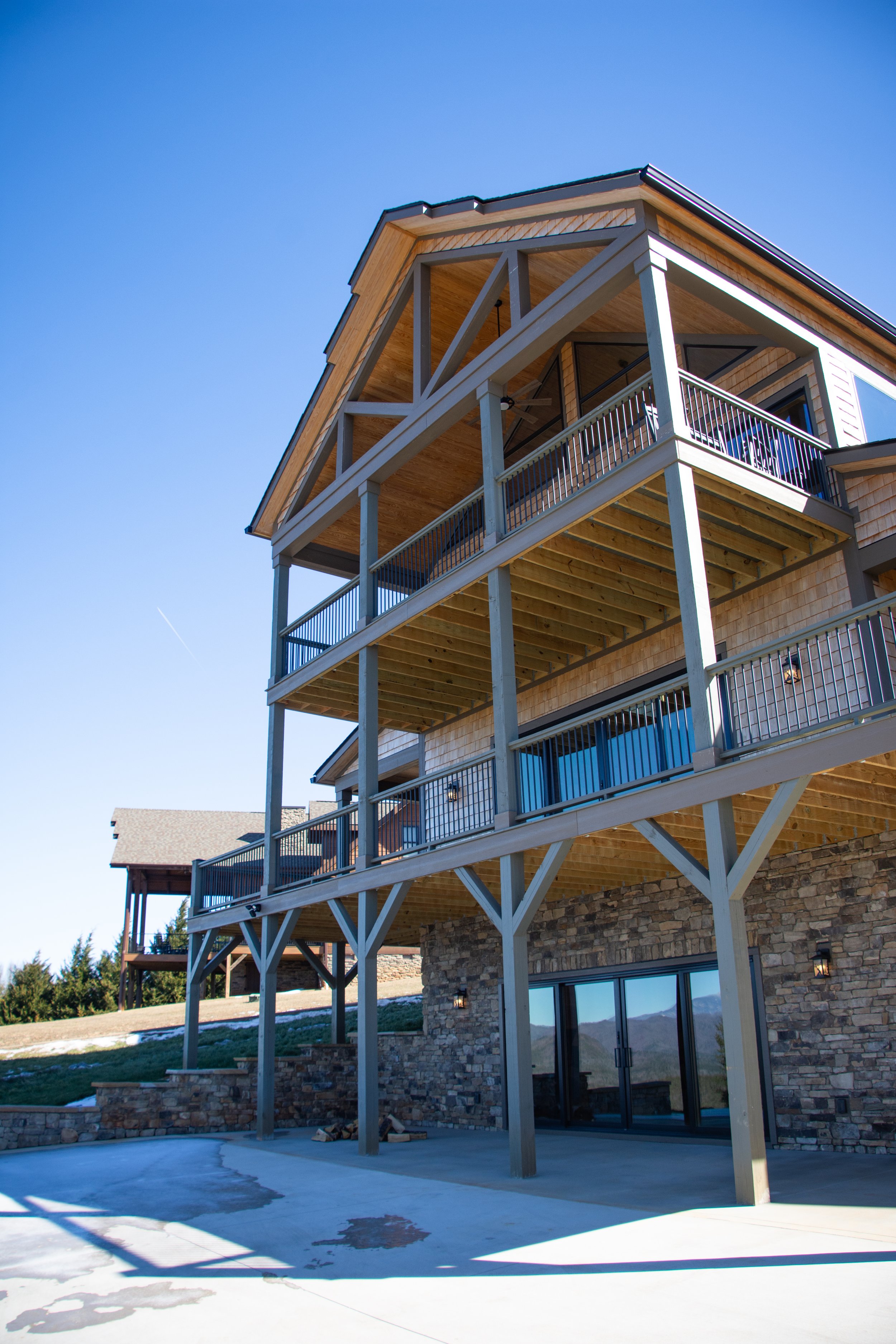 Multiple-story house built on stilts with balconies and large windows, blue sky in the background.