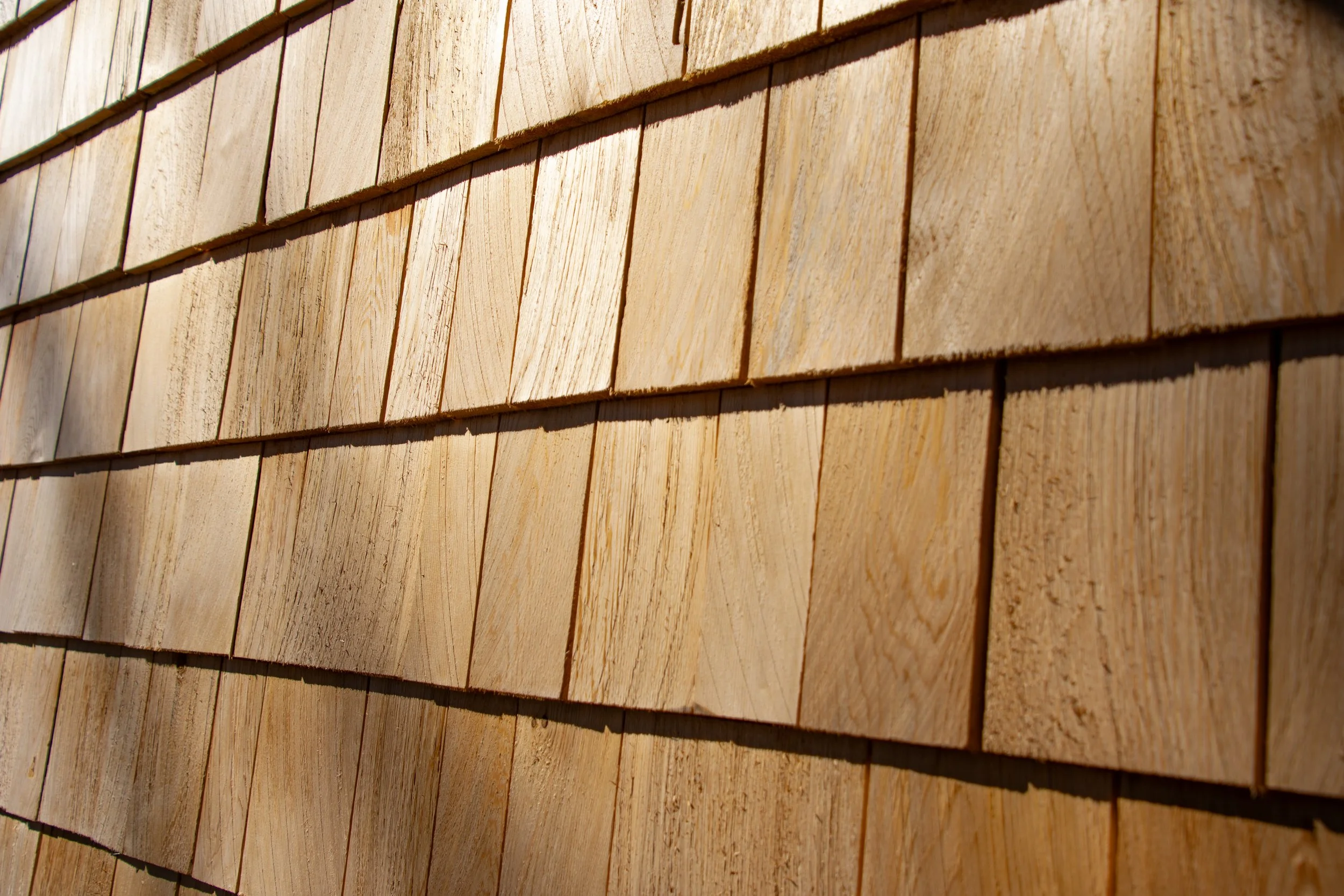 Close-up of wooden shingles on a building's exterior wall.