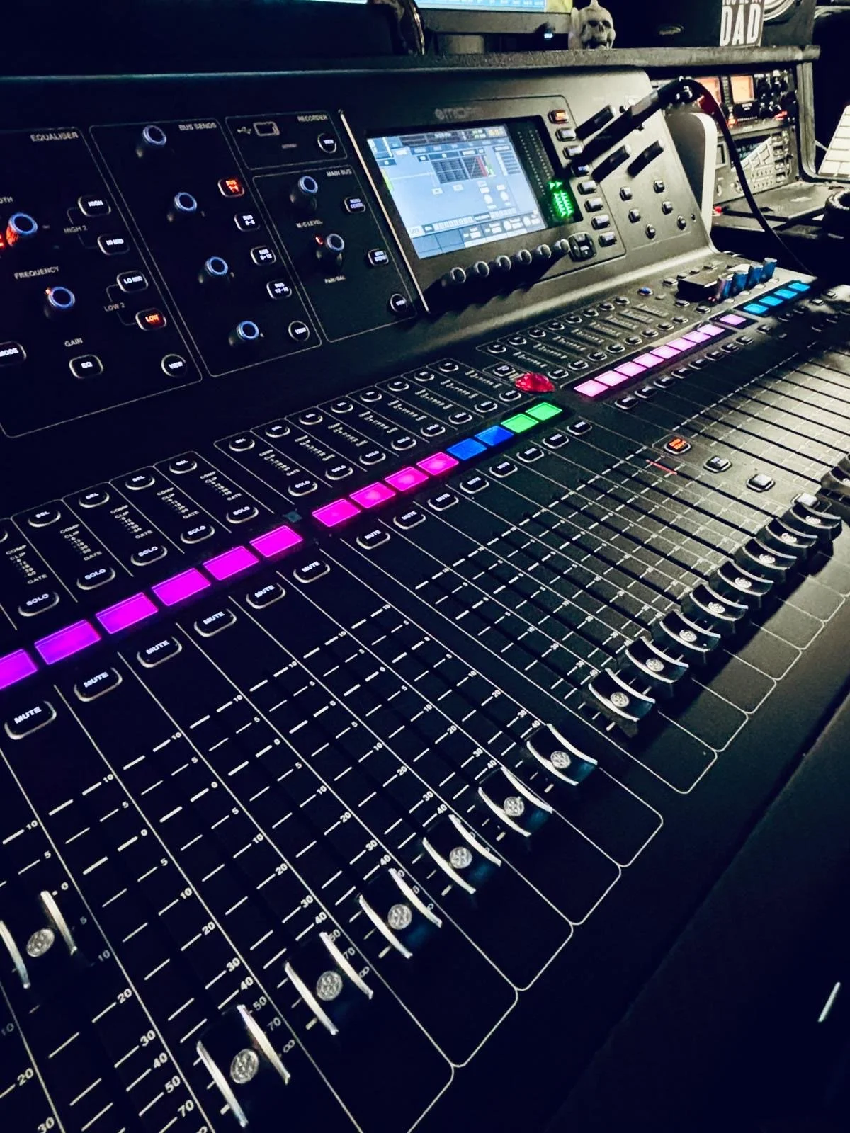 A digital audio mixing console with colorful illuminated buttons, knobs, and faders.