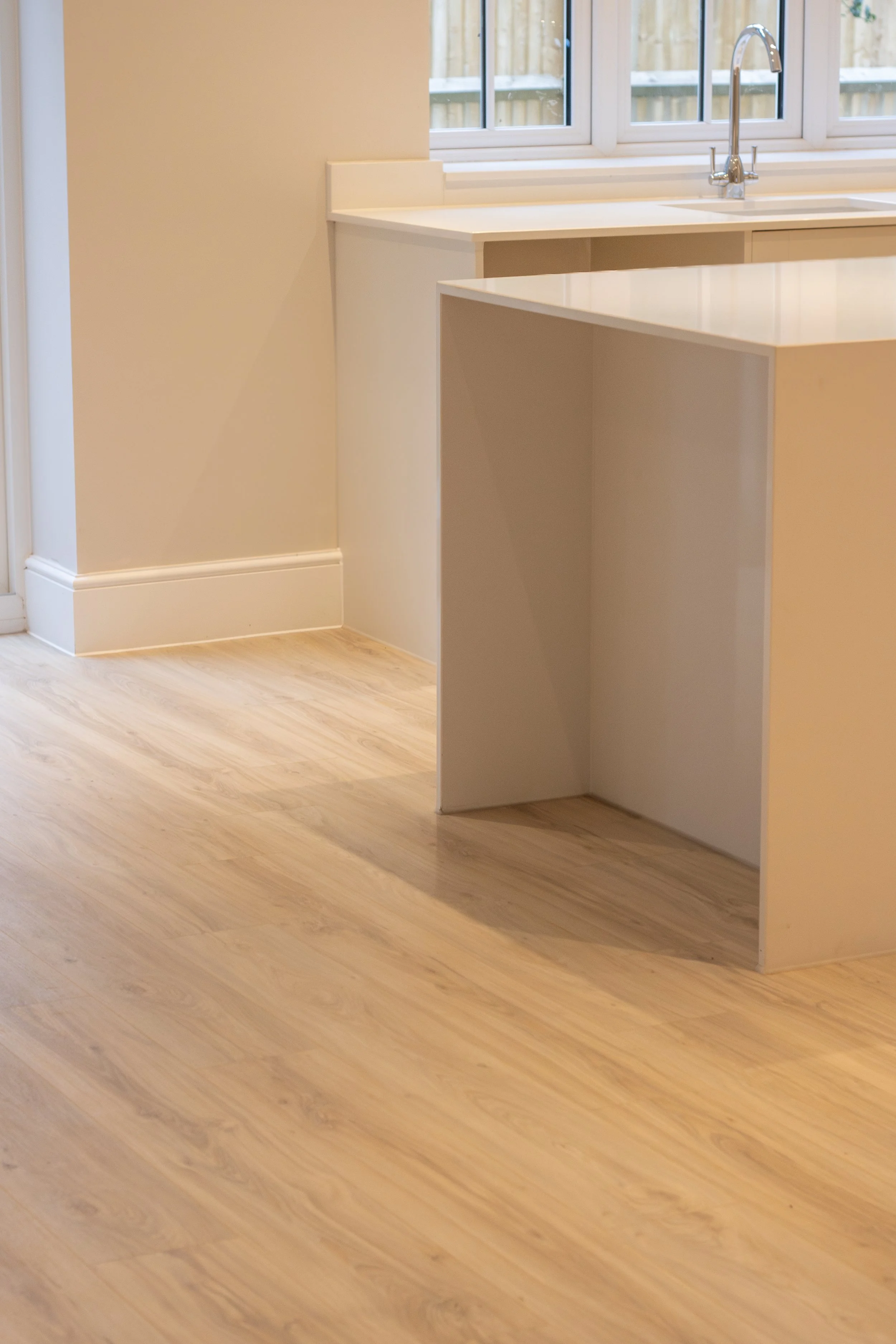 Empty kitchen corner with a white countertop and a window with a view of a wooden fence.