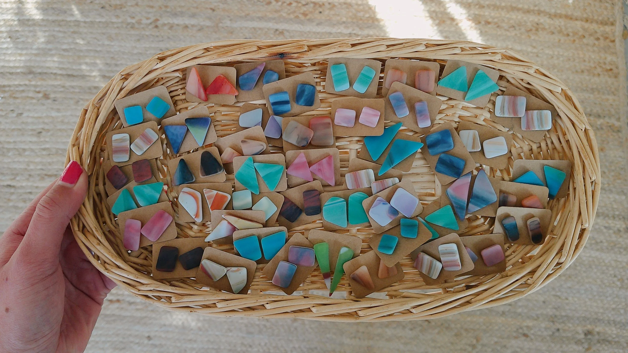 A hand holding a woven basket filled with various colorful geometric-shaped stickers.