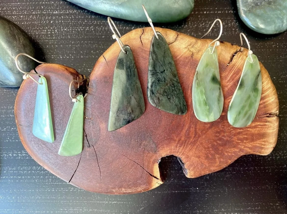 Collection of jade jewelry, including earrings and pendants, displayed on a wooden plate.