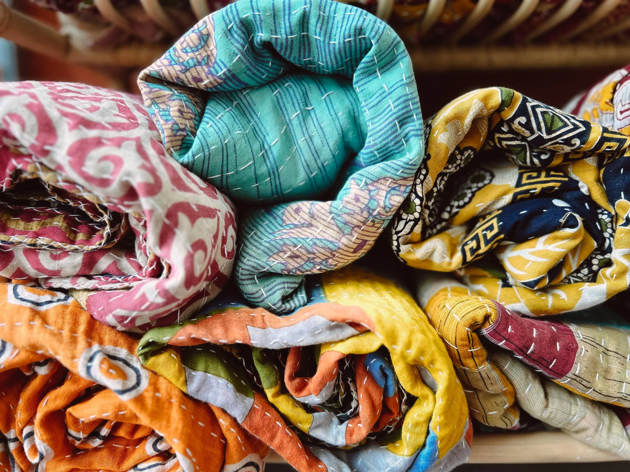 Colorful fabric bundles, including pink, blue, yellow, orange, and navy, rolled up tightly.