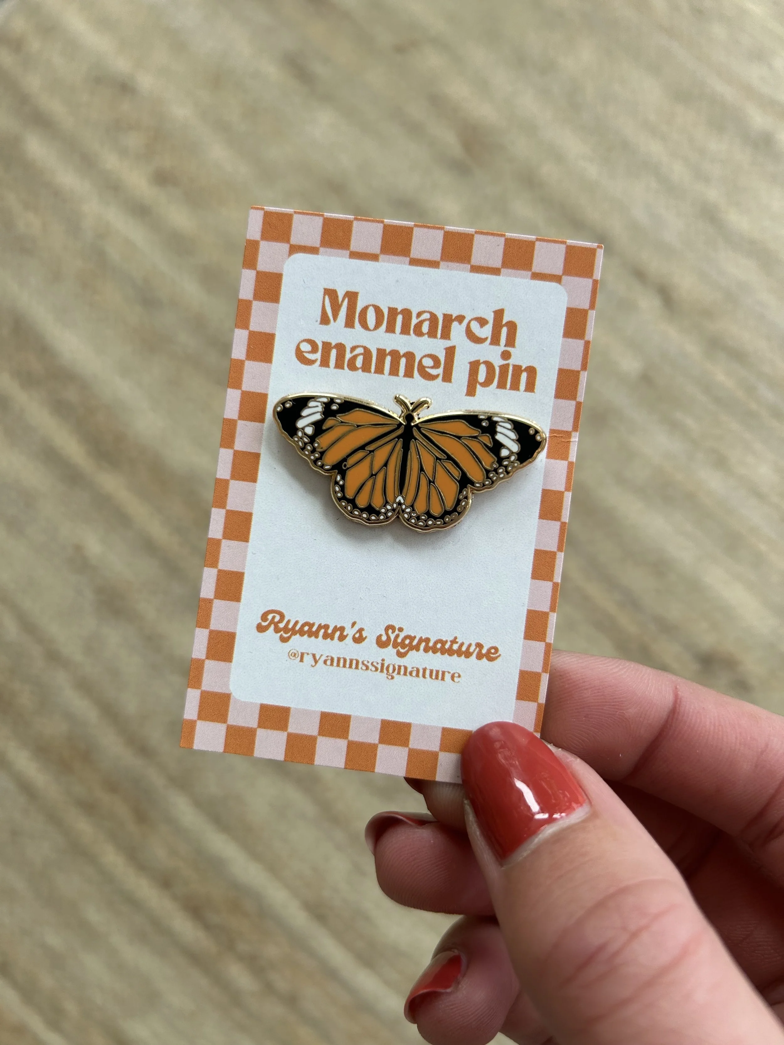 A Monarch enamel pin on a branded card that reads 'Monarch enamel pin' and 'Ryann's Signature @ryannssignature'.